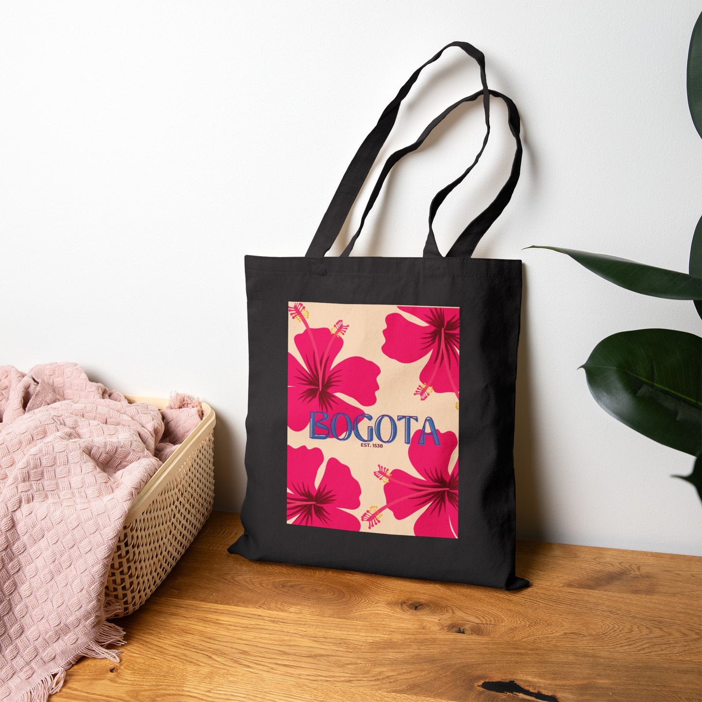 Black tote bag with pink floral design and 'Bogota' text on a wooden surface.