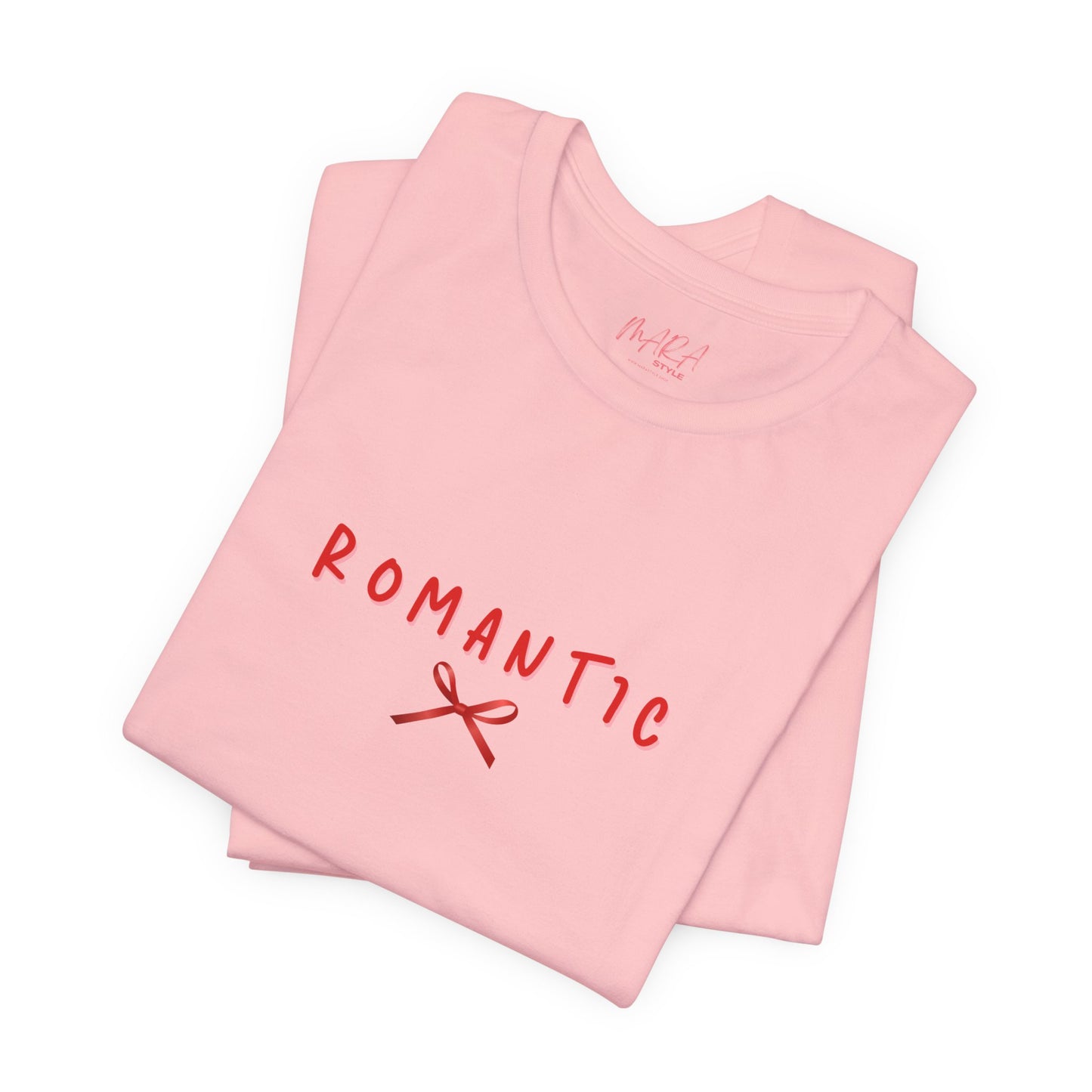Folded pink t-shirt with 'ROMANTIC' and a bow graphic on a white background