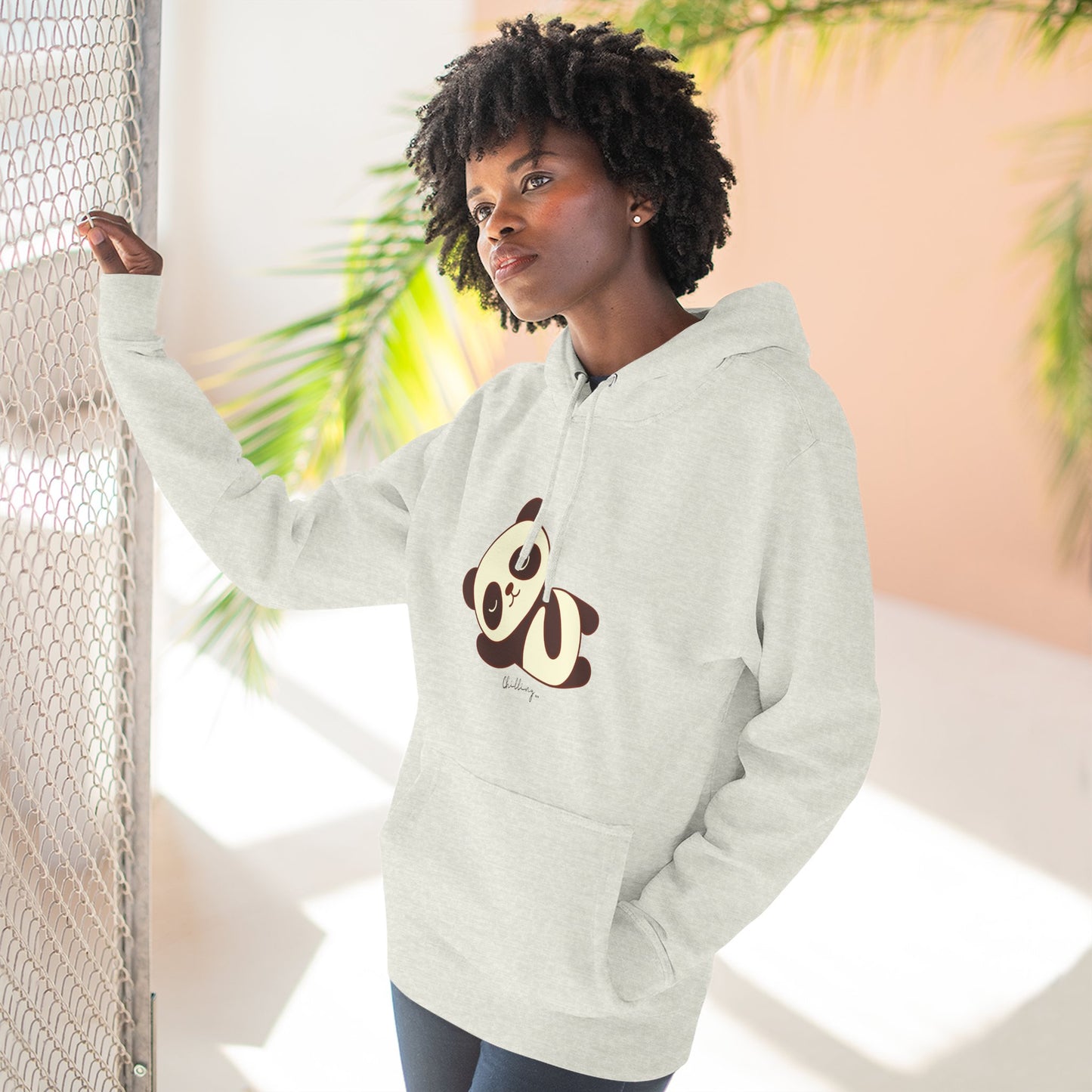 Person wearing a light gray hoodie with a panda design, standing against a neutral background.