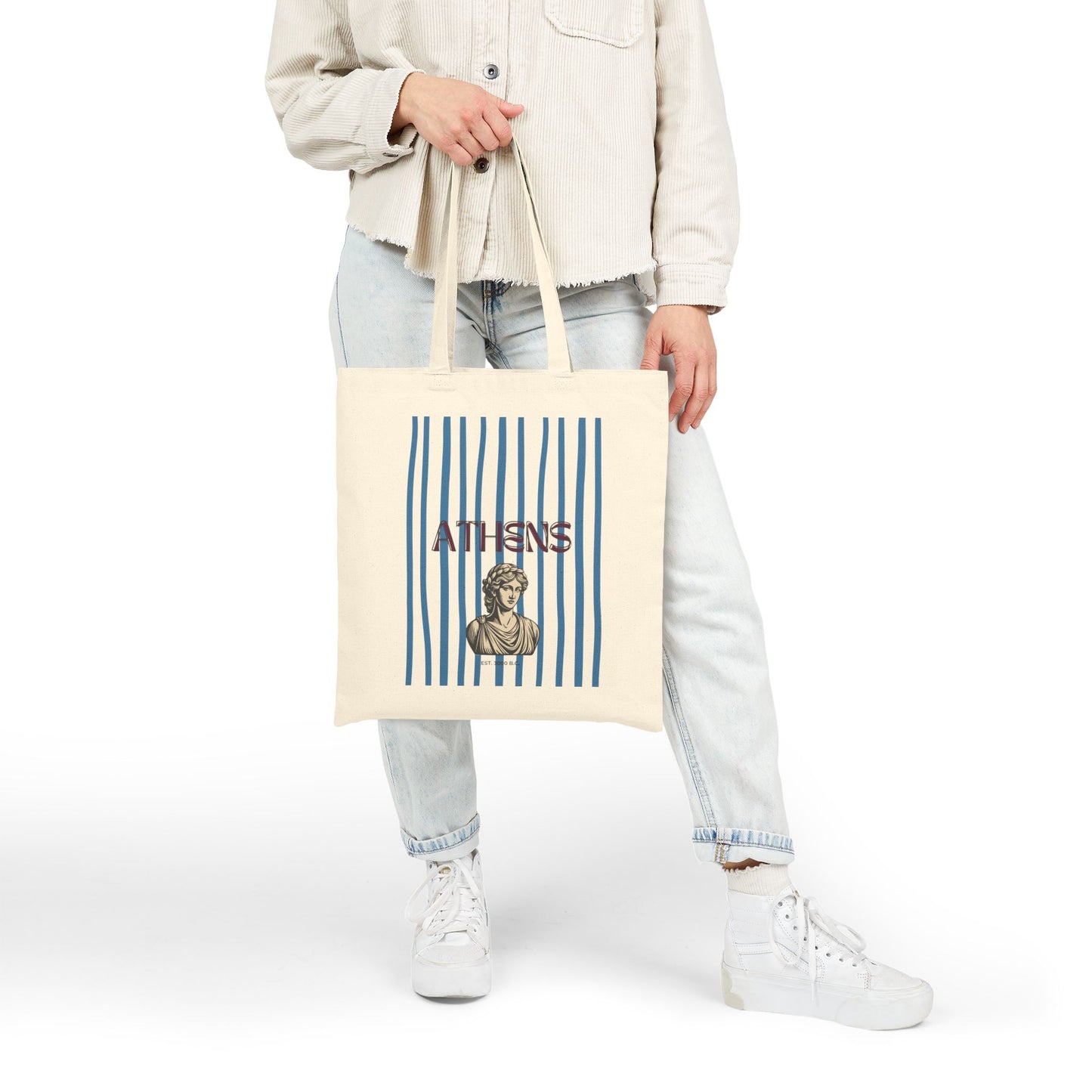 Person holding a tote bag with 'Athens' design on a white background