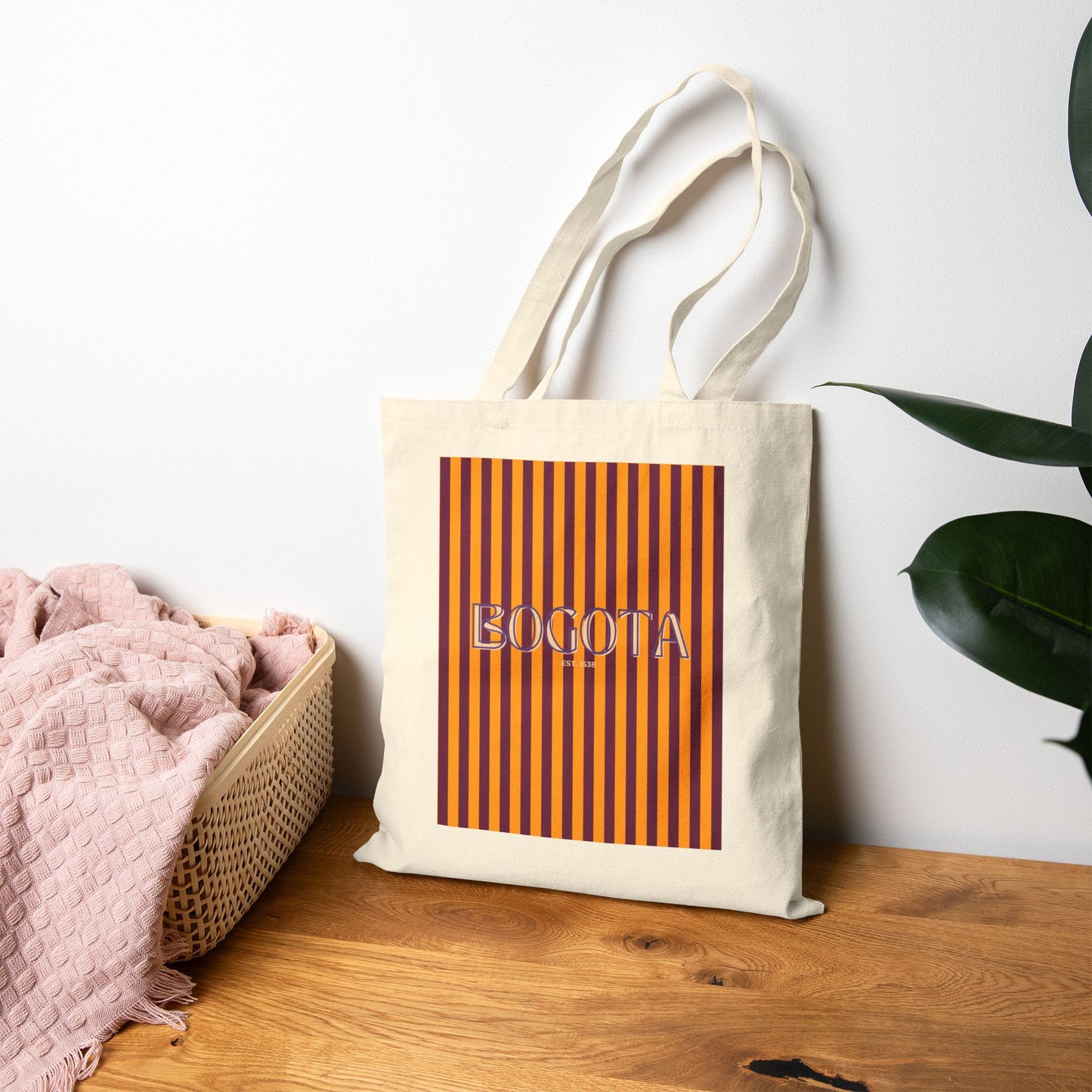 Tote bag with 'BOGOTA' design on a wooden surface with a plant in the background