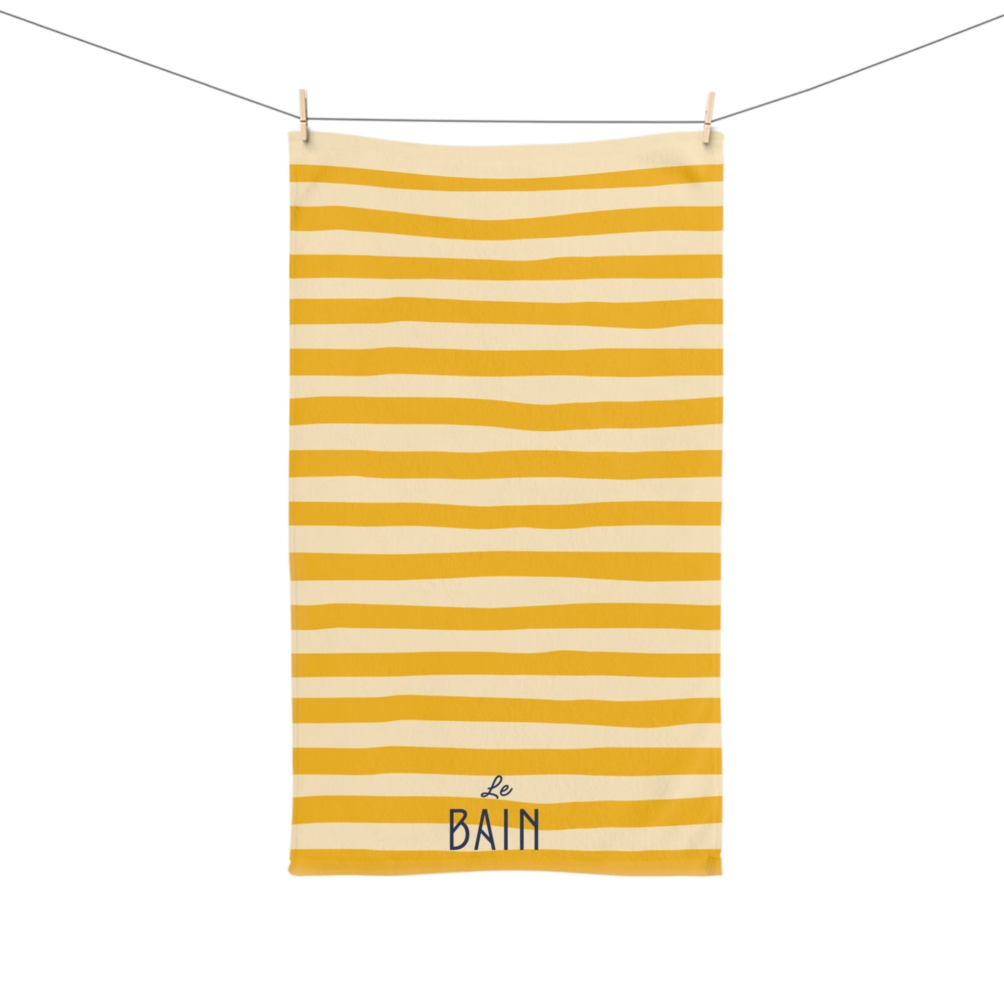 Yellow and white striped towel with 'Le Bain' text hanging on a line.