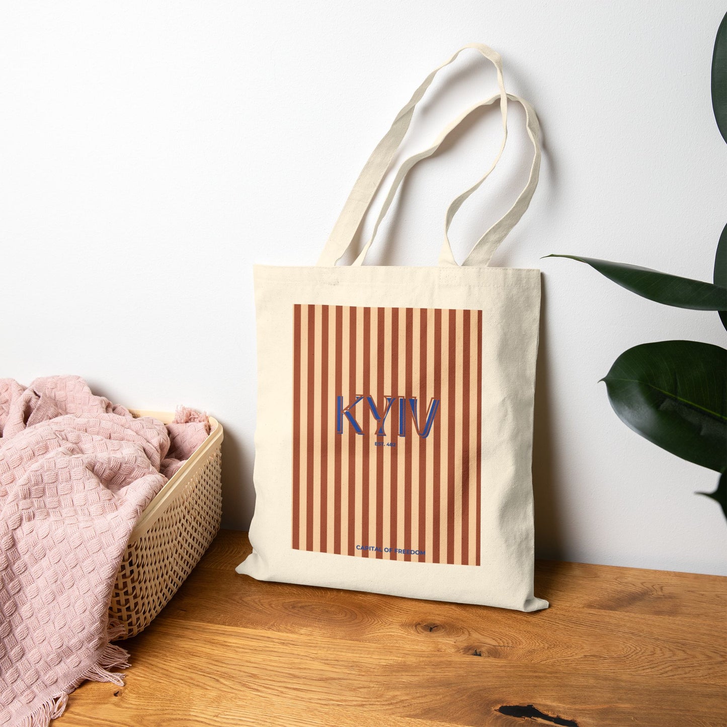 Tote bag with 'KYIV' design on a wooden surface with a plant in the background