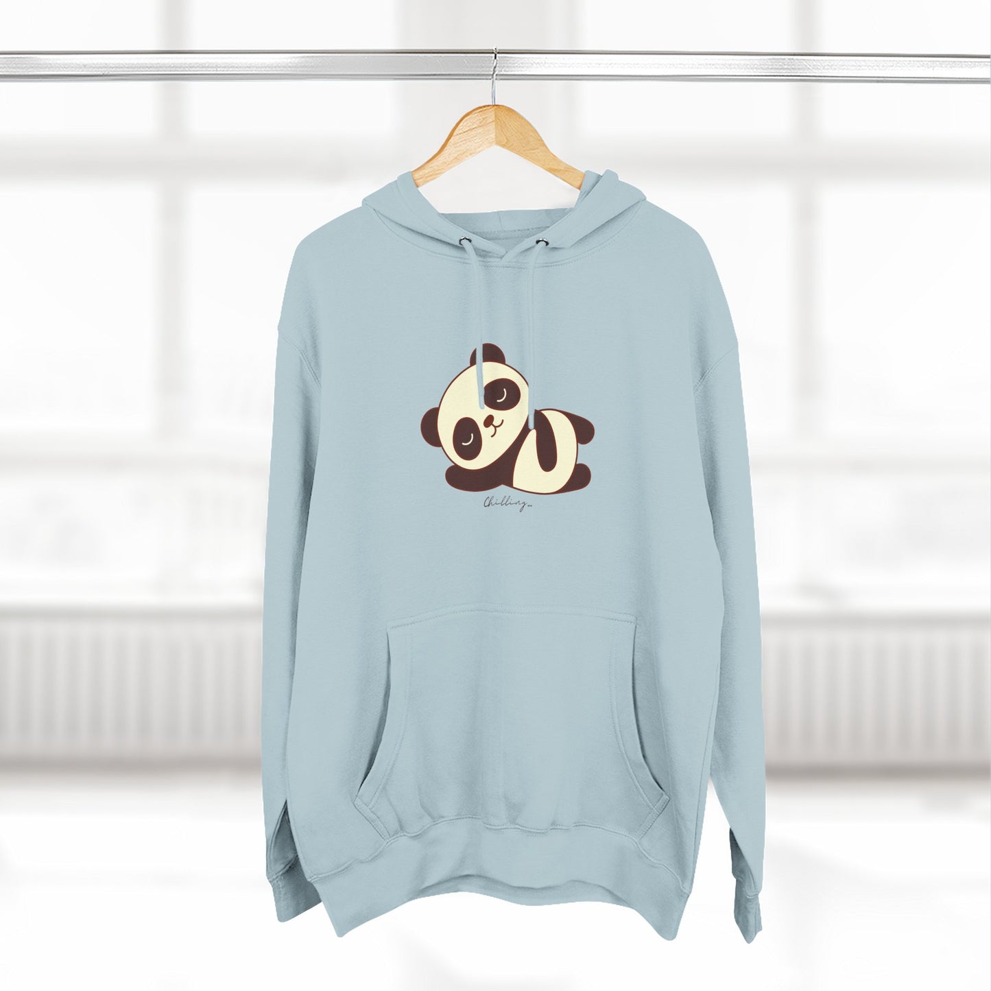 Light blue hoodie with a panda design on a hanger against a white wall.