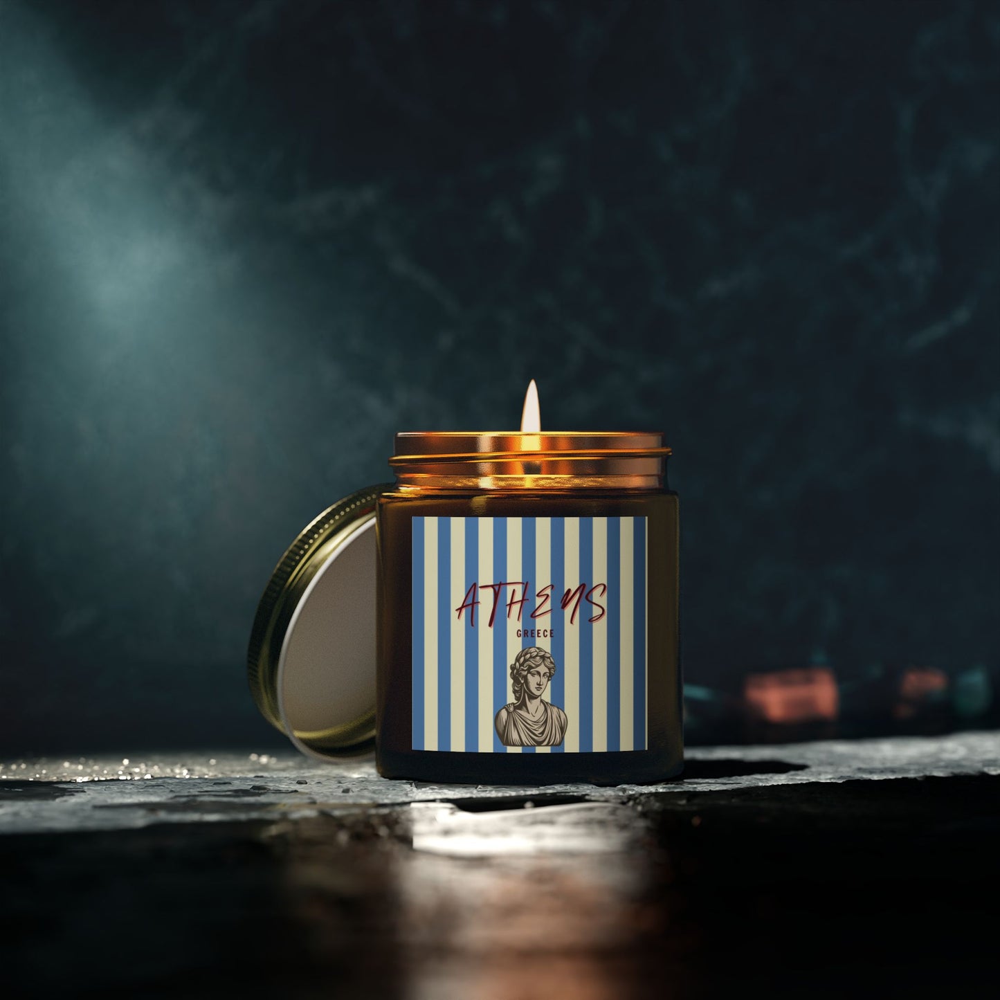 Candle in a jar with a 'Athens' label on a dark background