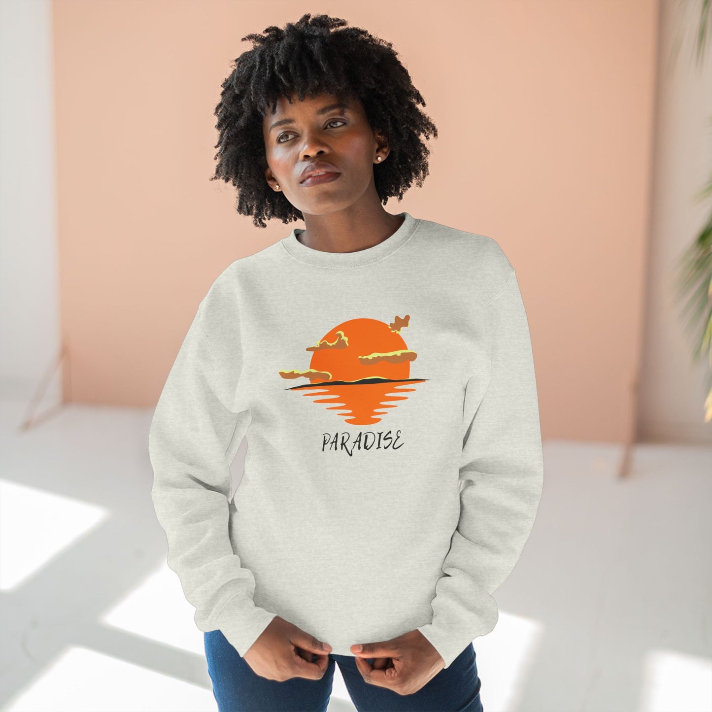 Person wearing a white sweatshirt with a sunset and palm tree design, standing against a light background.