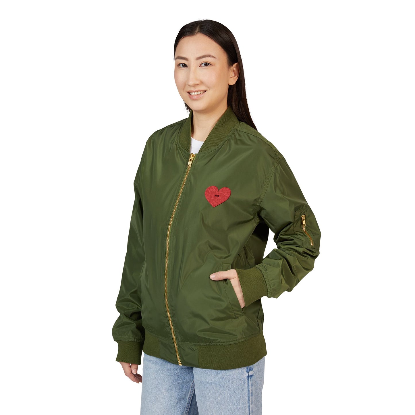 Woman wearing a green bomber jacket with a red heart emblem on a white background