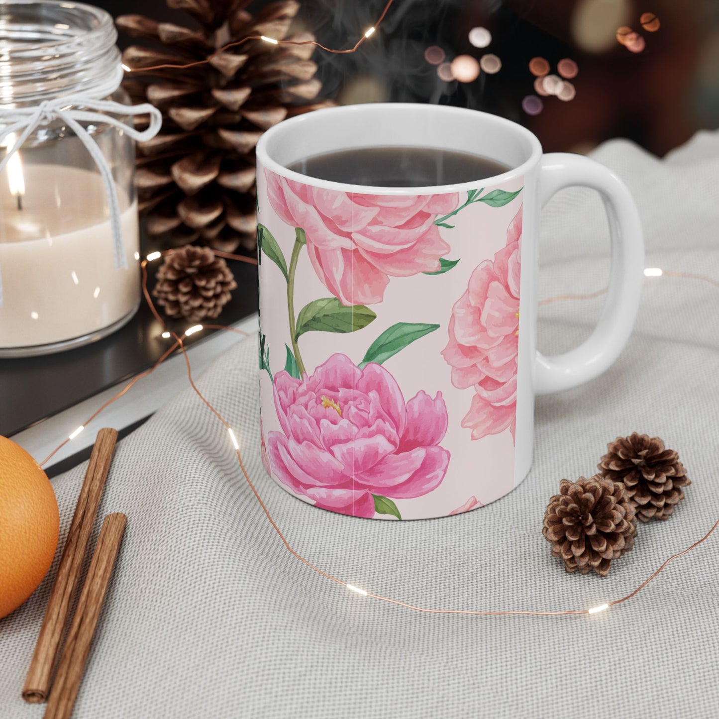 White mug with pink floral design on a table with decorative items