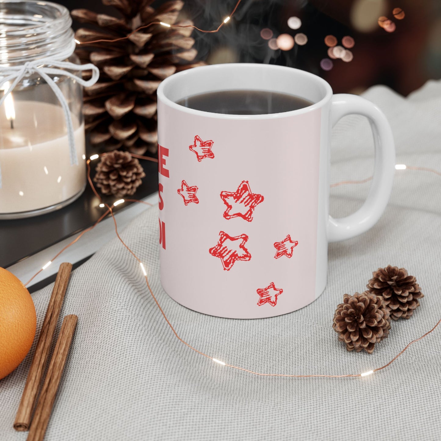 White mug with red star patterns on a table with decorative items