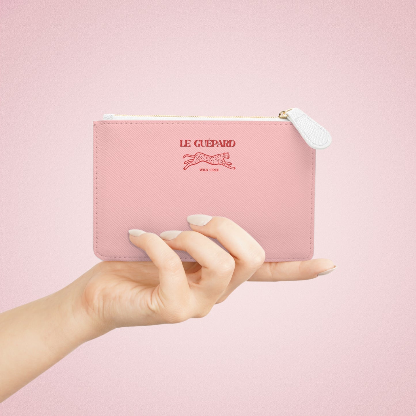 Pink wallet with 'Le Guepard' branding held by a hand against a pink background