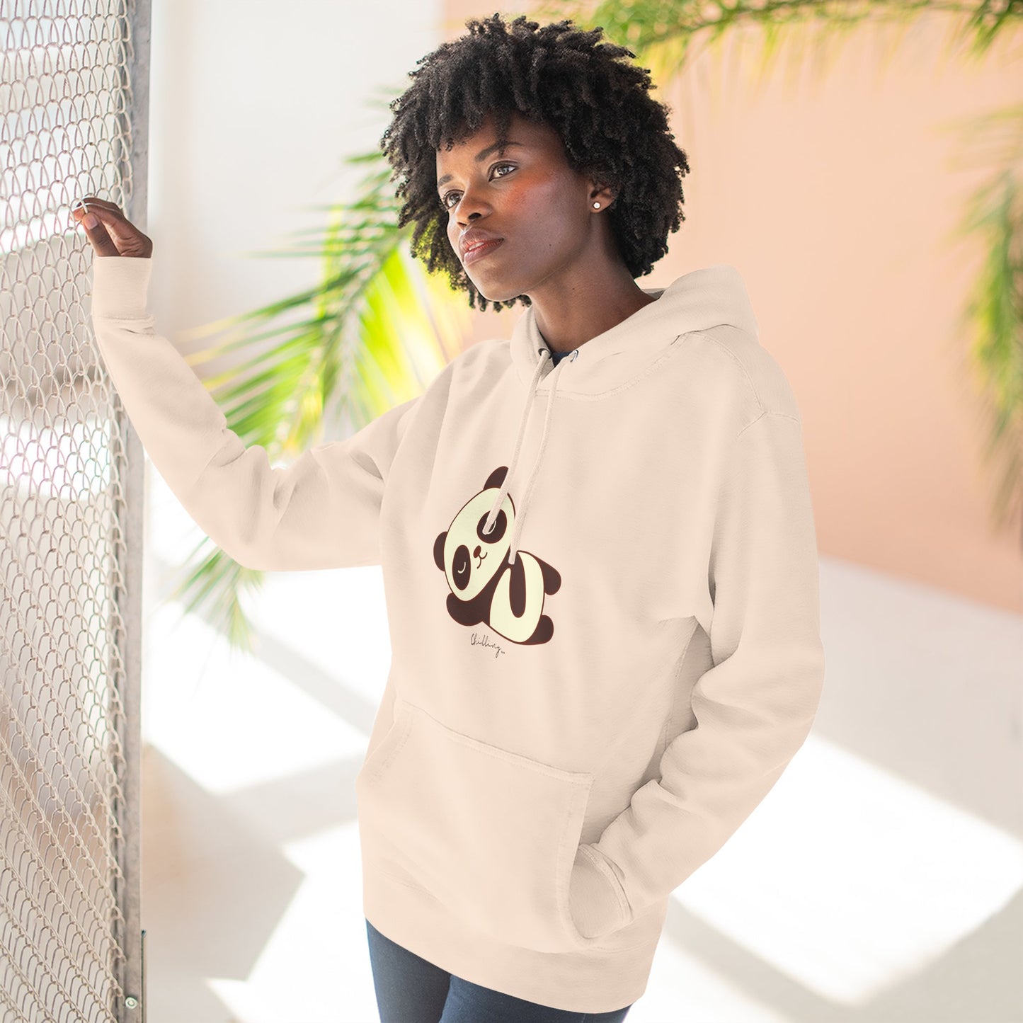 Person wearing a beige hoodie with a panda design in an outdoor setting