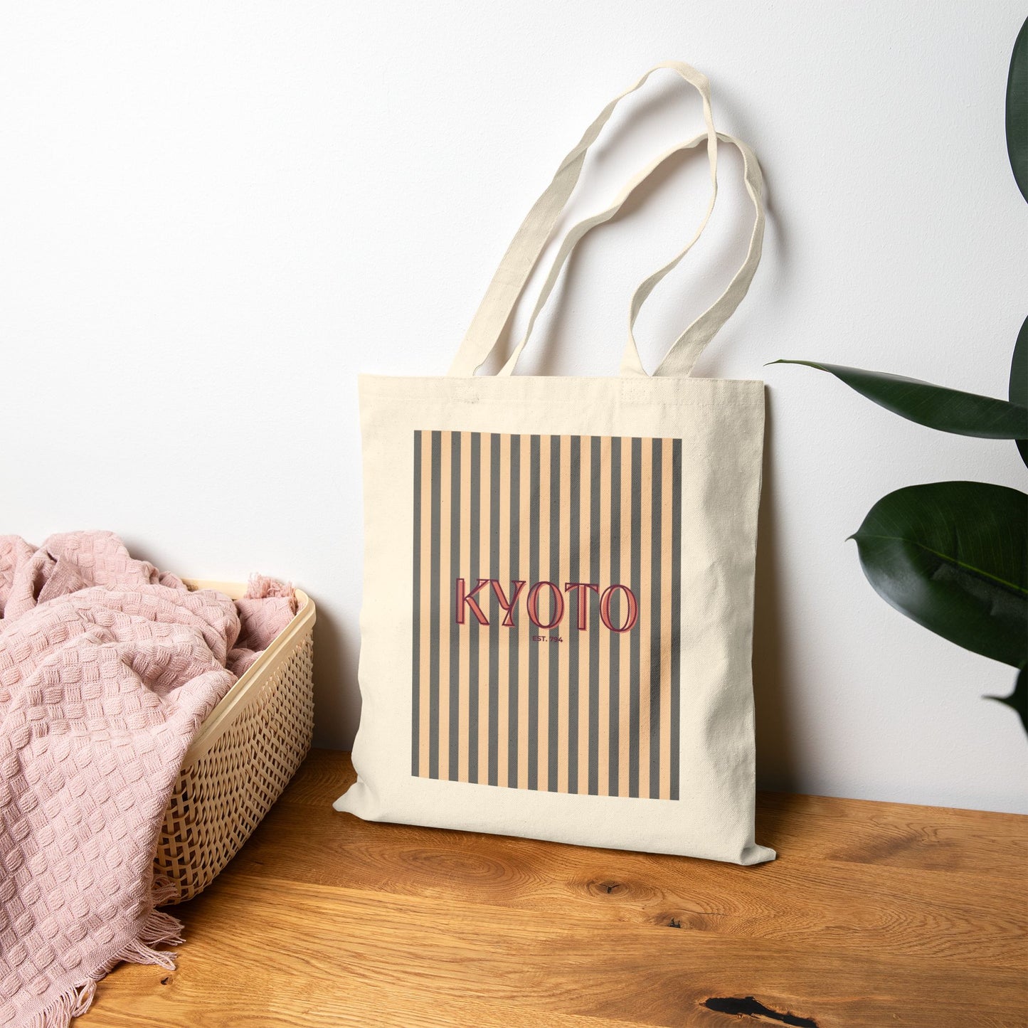 Tote bag with 'KYOTO' text on a wooden surface with a plant in the background