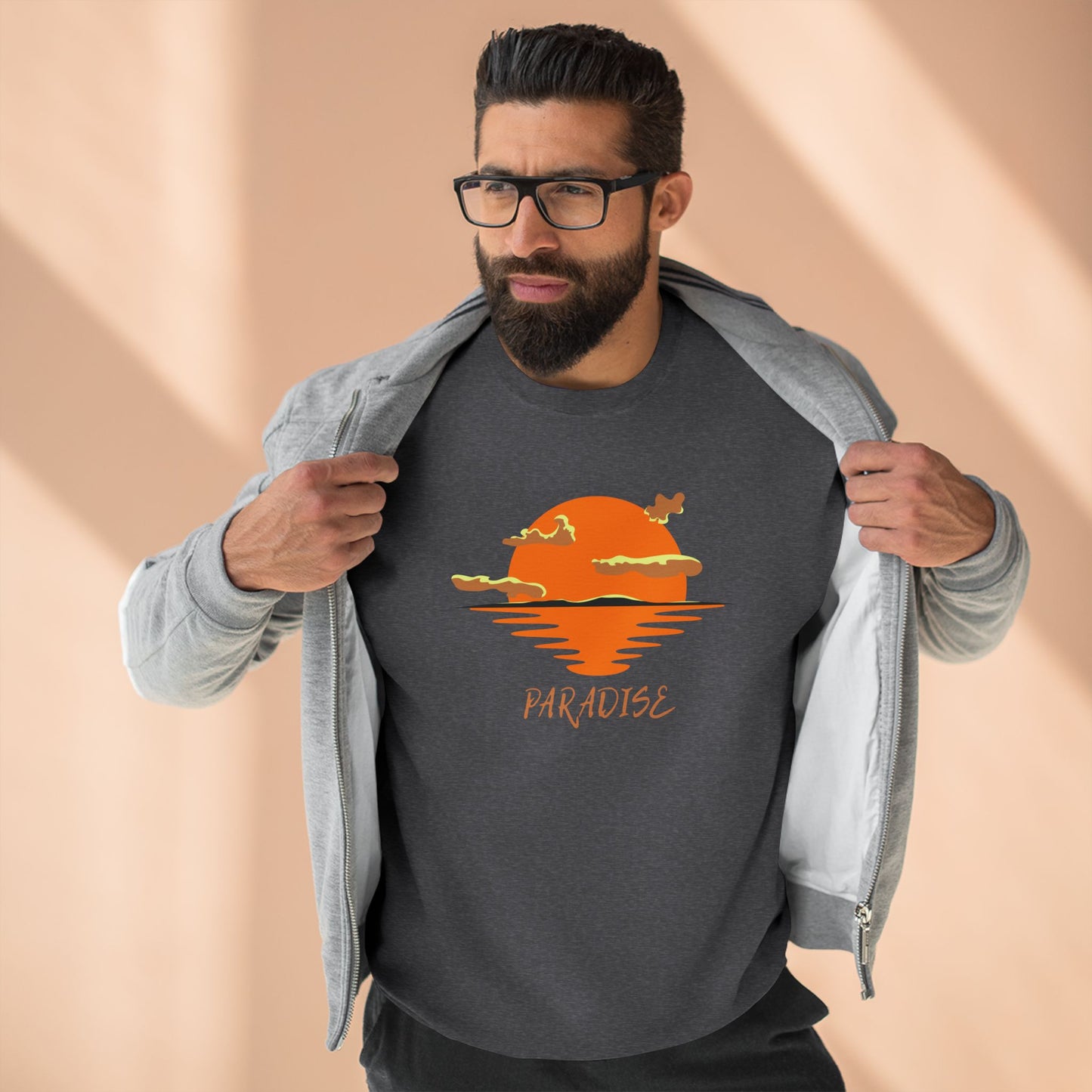Man wearing a dark gray t-shirt with a sunset design and 'Paradise' text, holding a light gray jacket.