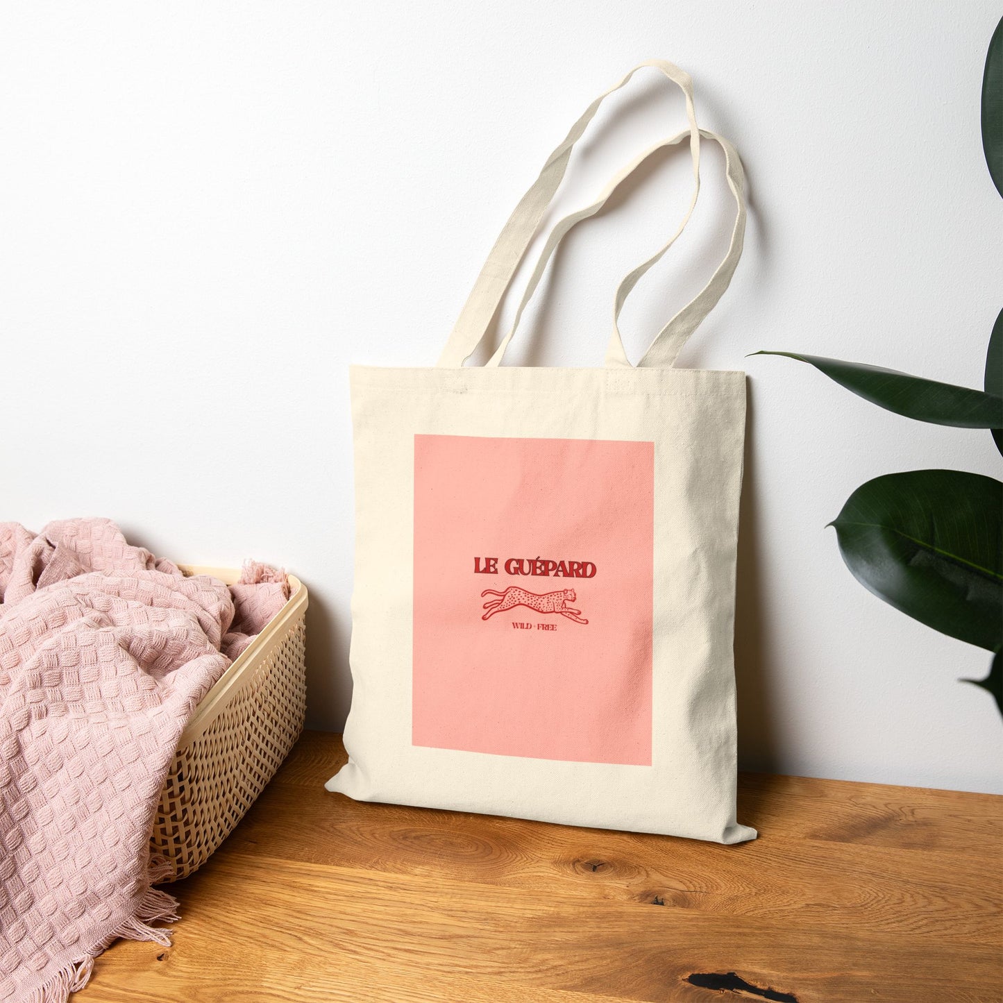 Tote bag with pink design and 'Le Guépard' logo on a wooden surface.
