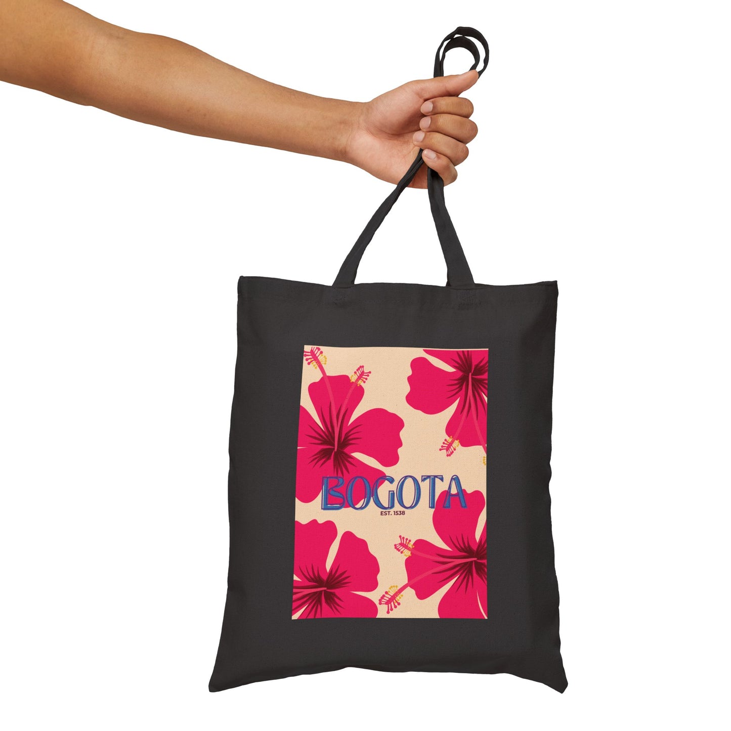 Black tote bag with pink floral design and 'Bogota' text held by a hand on a white background