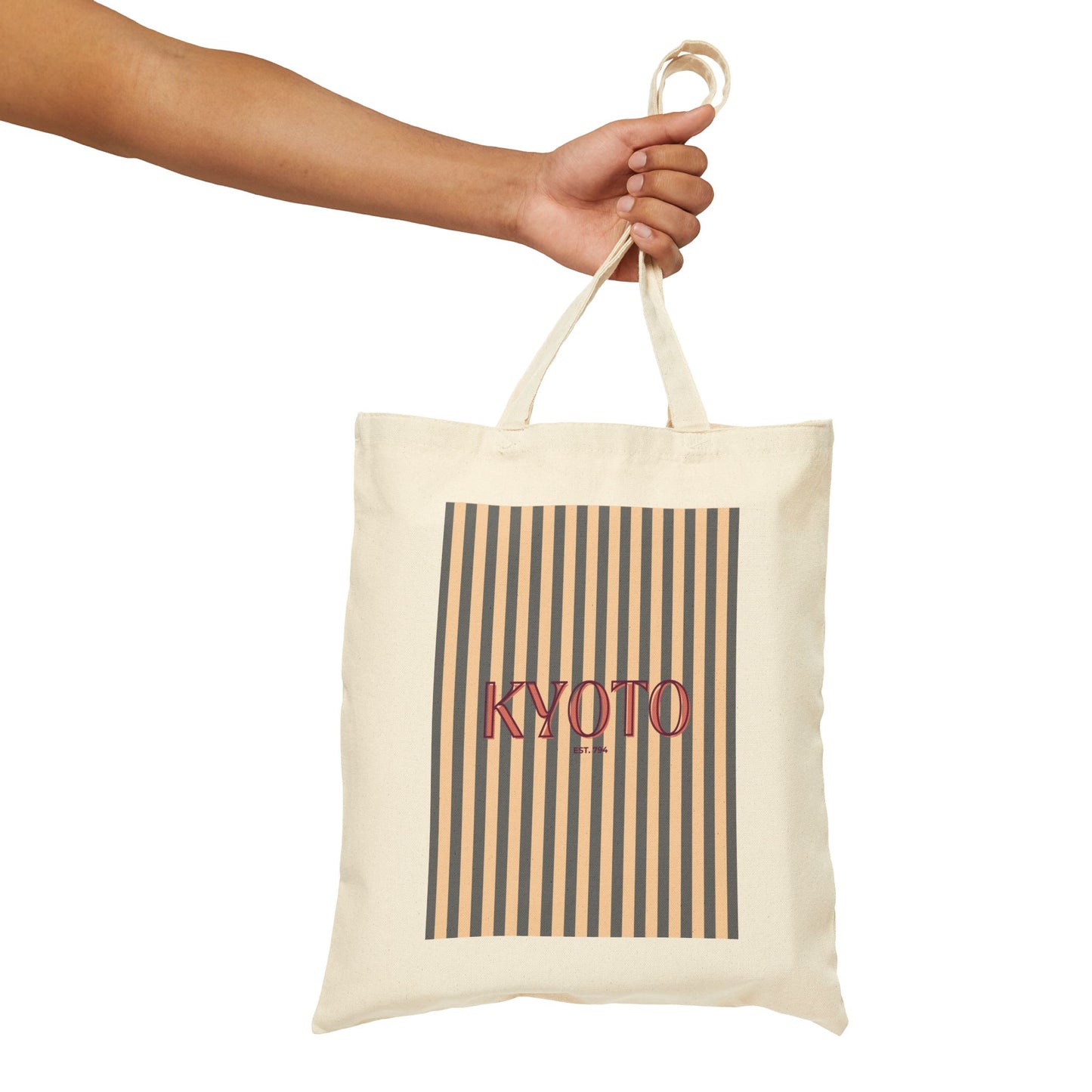 Tote bag with 'KYOTO' text and striped design held by a hand on a white background