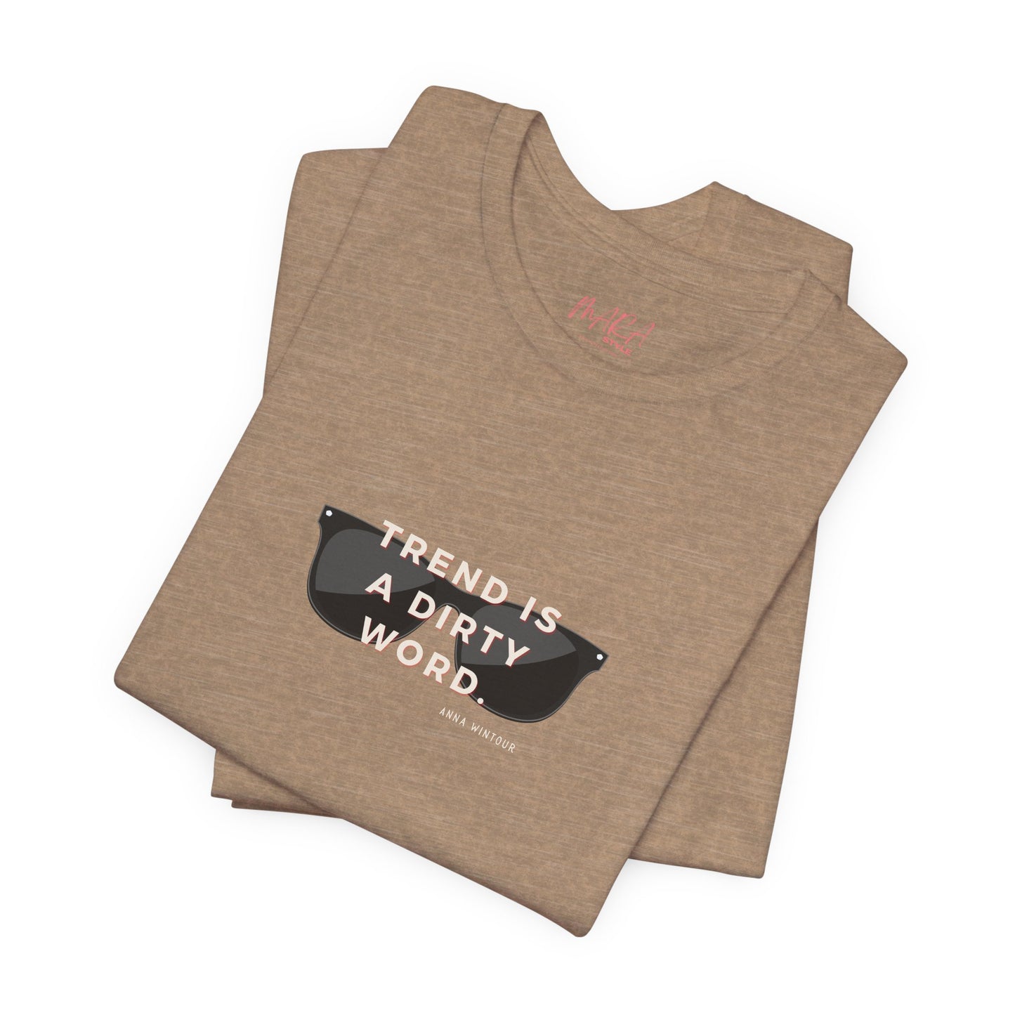 Folded brown t-shirt with sunglasses graphic and Anna Wintour Quote on a white background