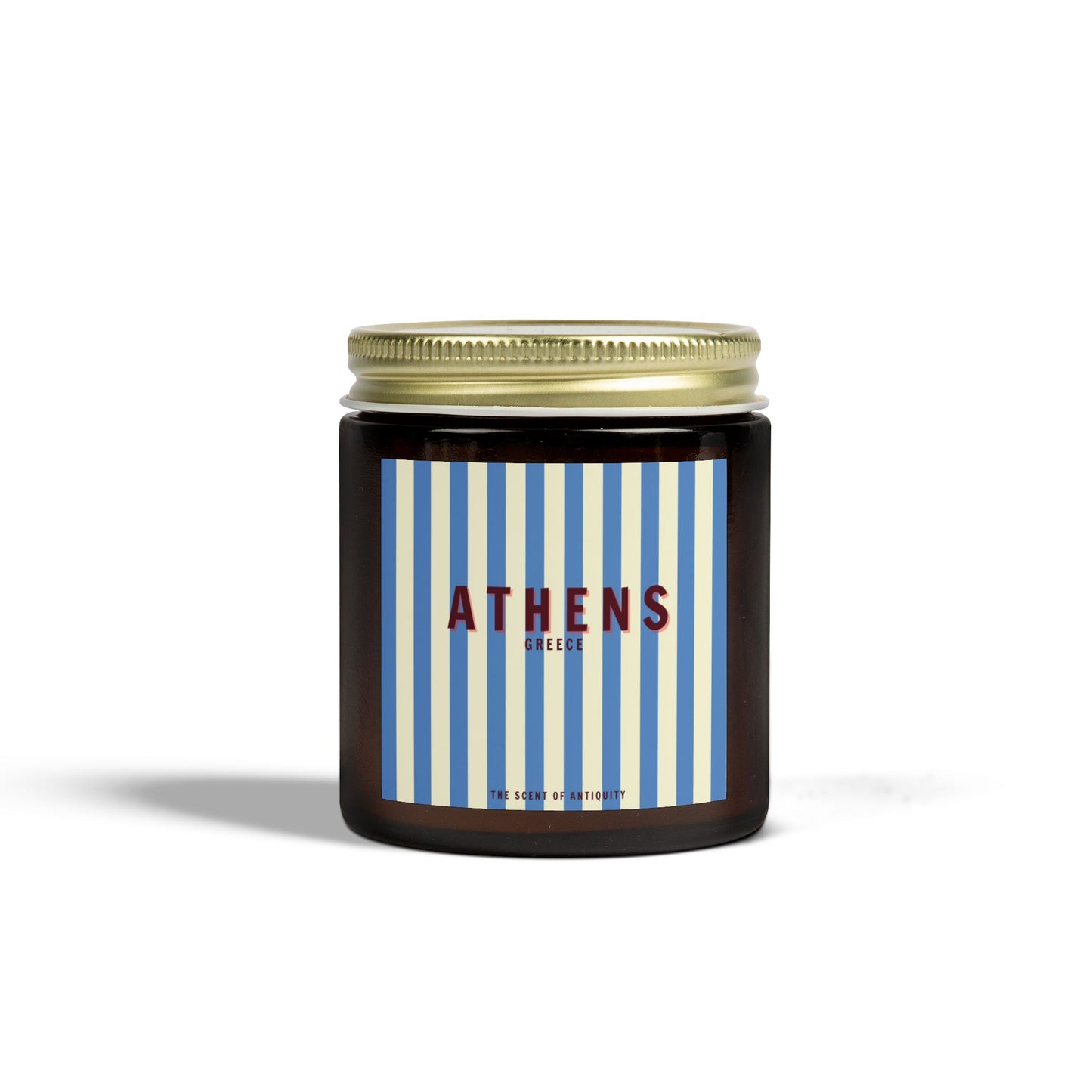 A striped glass candle vessel with a gold lid, labeled 'ATHENS' in red lettering against a blue striped background.