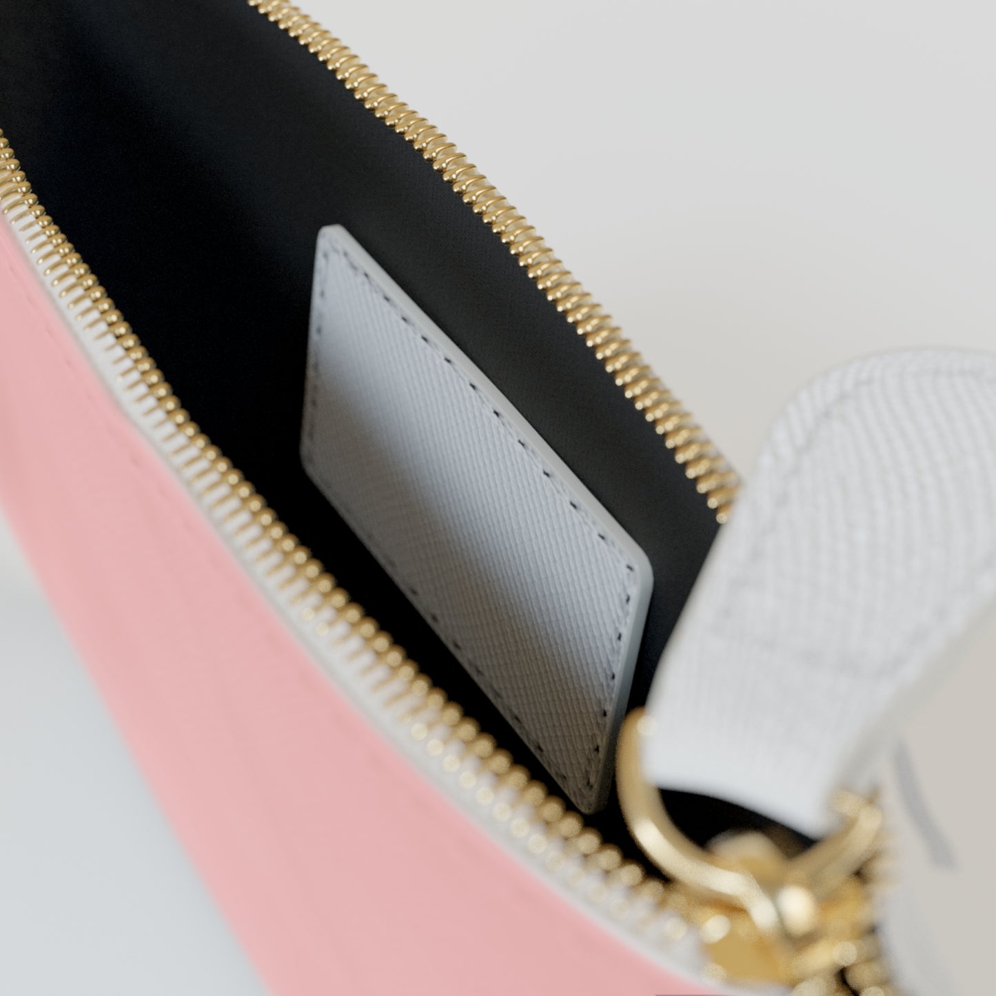Close-up of a pink and black handbag with gold zipper and handle.