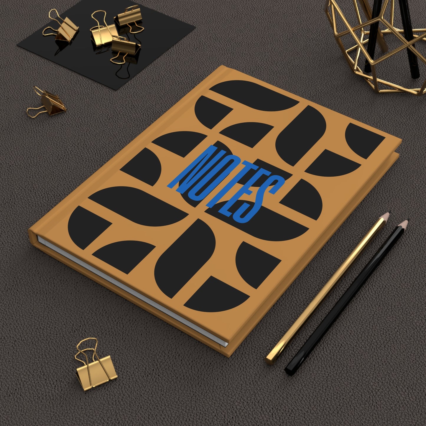 Notebook with decorative cover on a dark surface with office supplies.