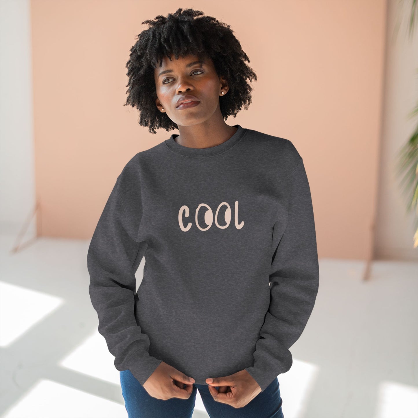 Woman wearing a gray sweatshirt with 'COOL' printed on it against a light background