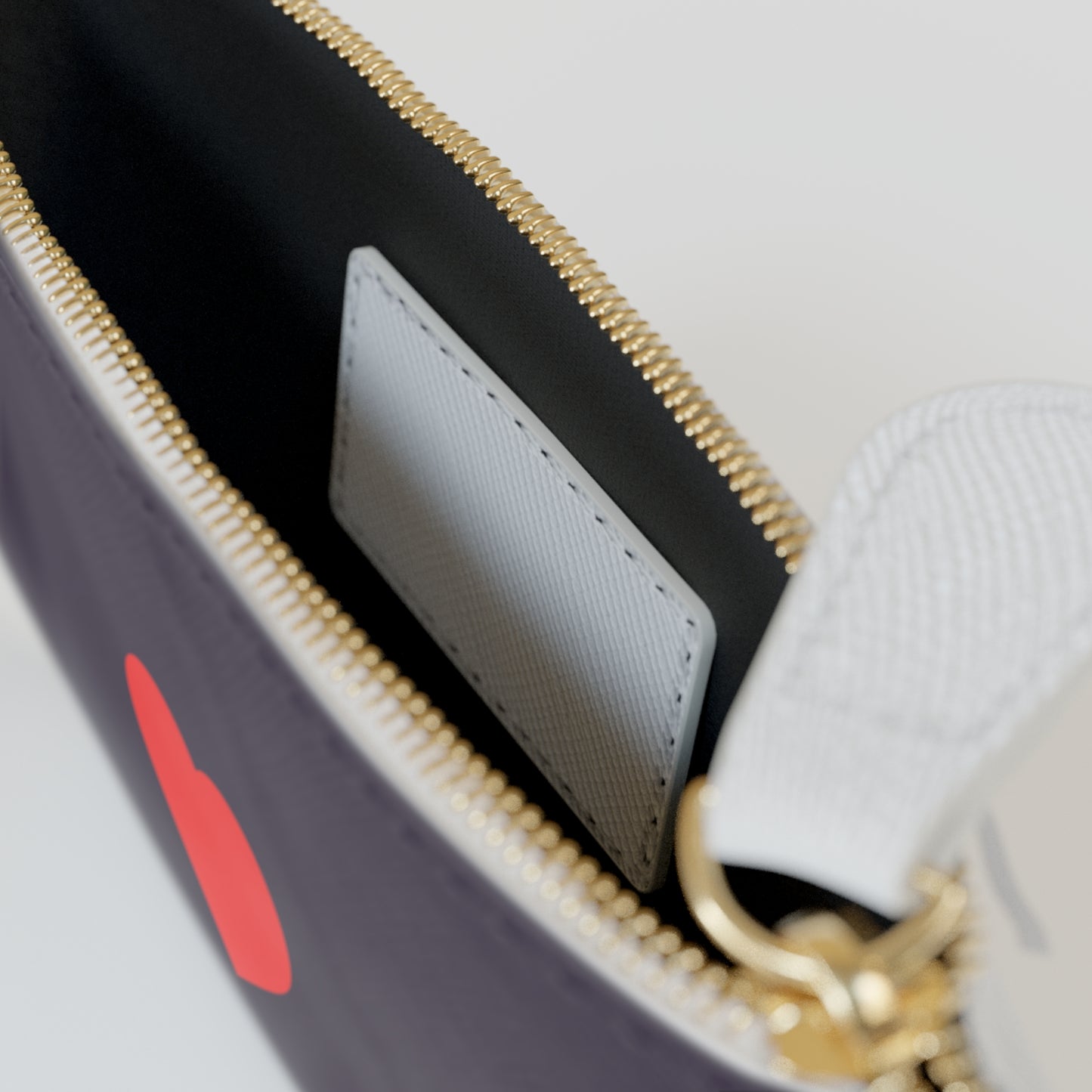 Close-up of a handbag with a gold zipper and red heart design.