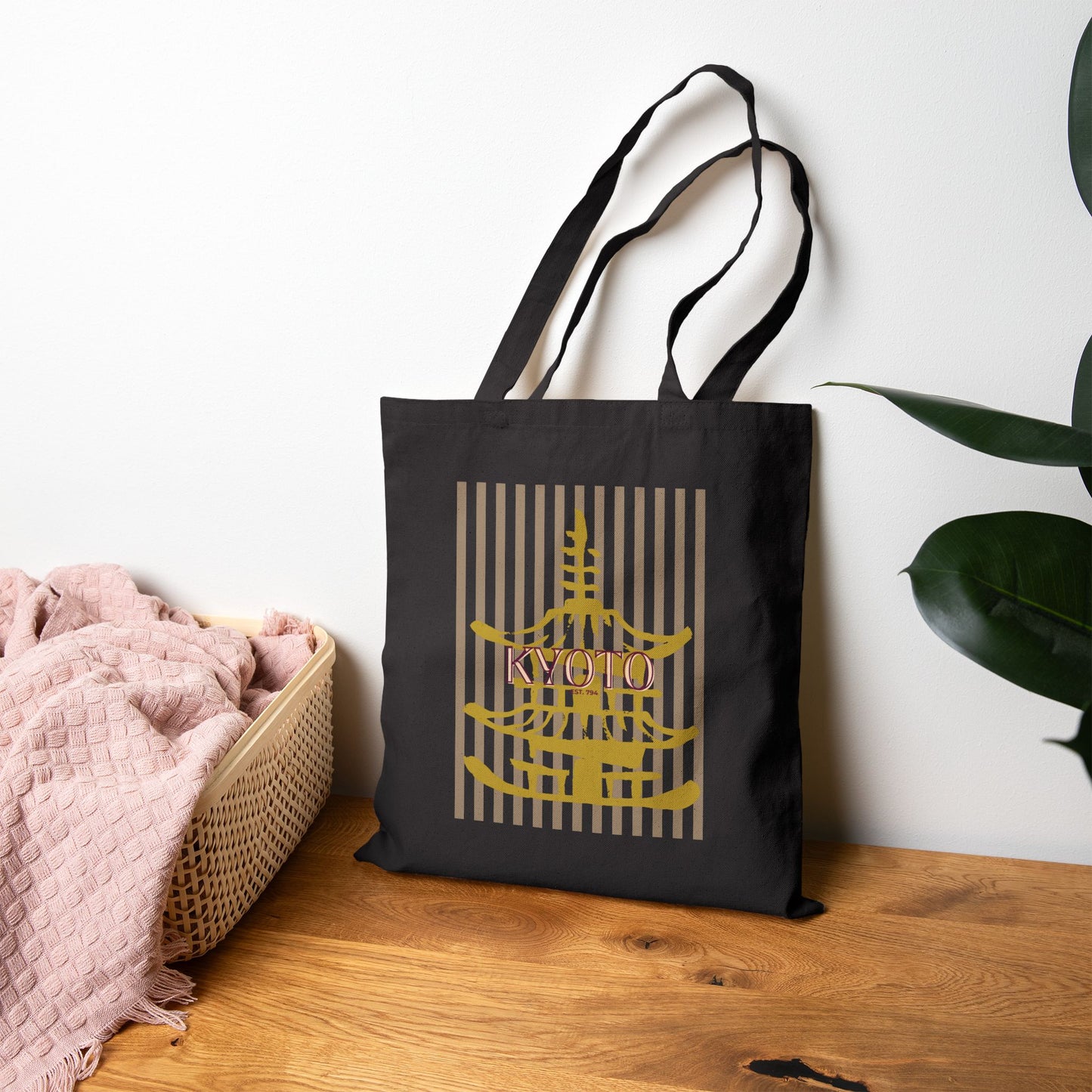 Black tote bag with 'Kyoto' design on a wooden surface with a plant in the background