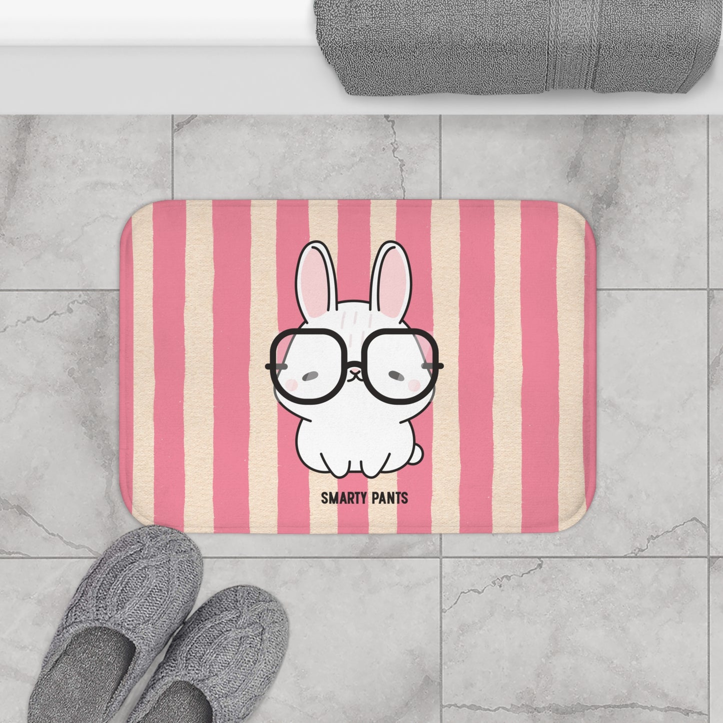Striped bath mat with a cartoon bunny wearing glasses and 'Smarty Pants' text, placed on a tiled floor.