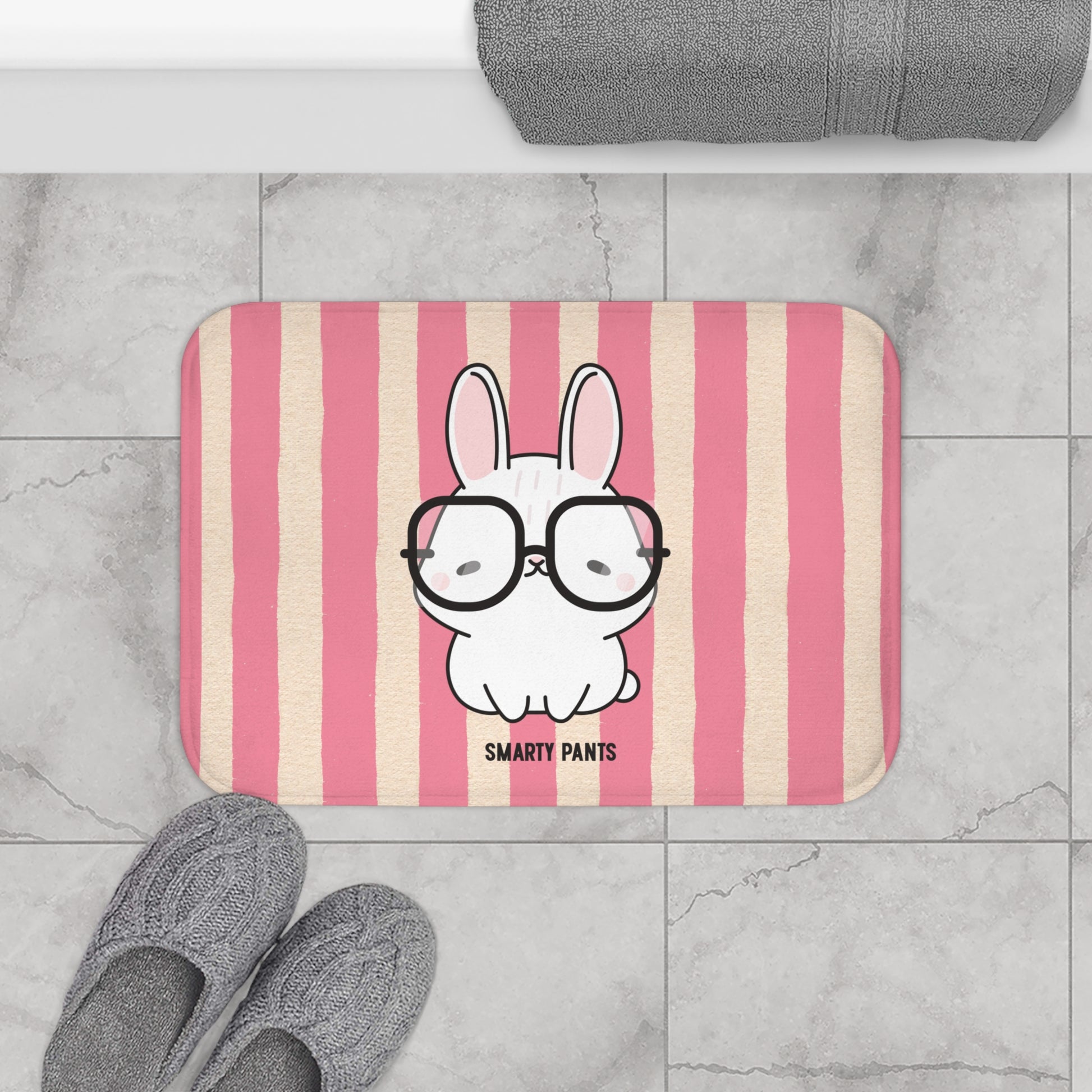 Striped bath mat with a cartoon bunny wearing glasses and 'Smarty Pants' text, placed on a tiled floor.