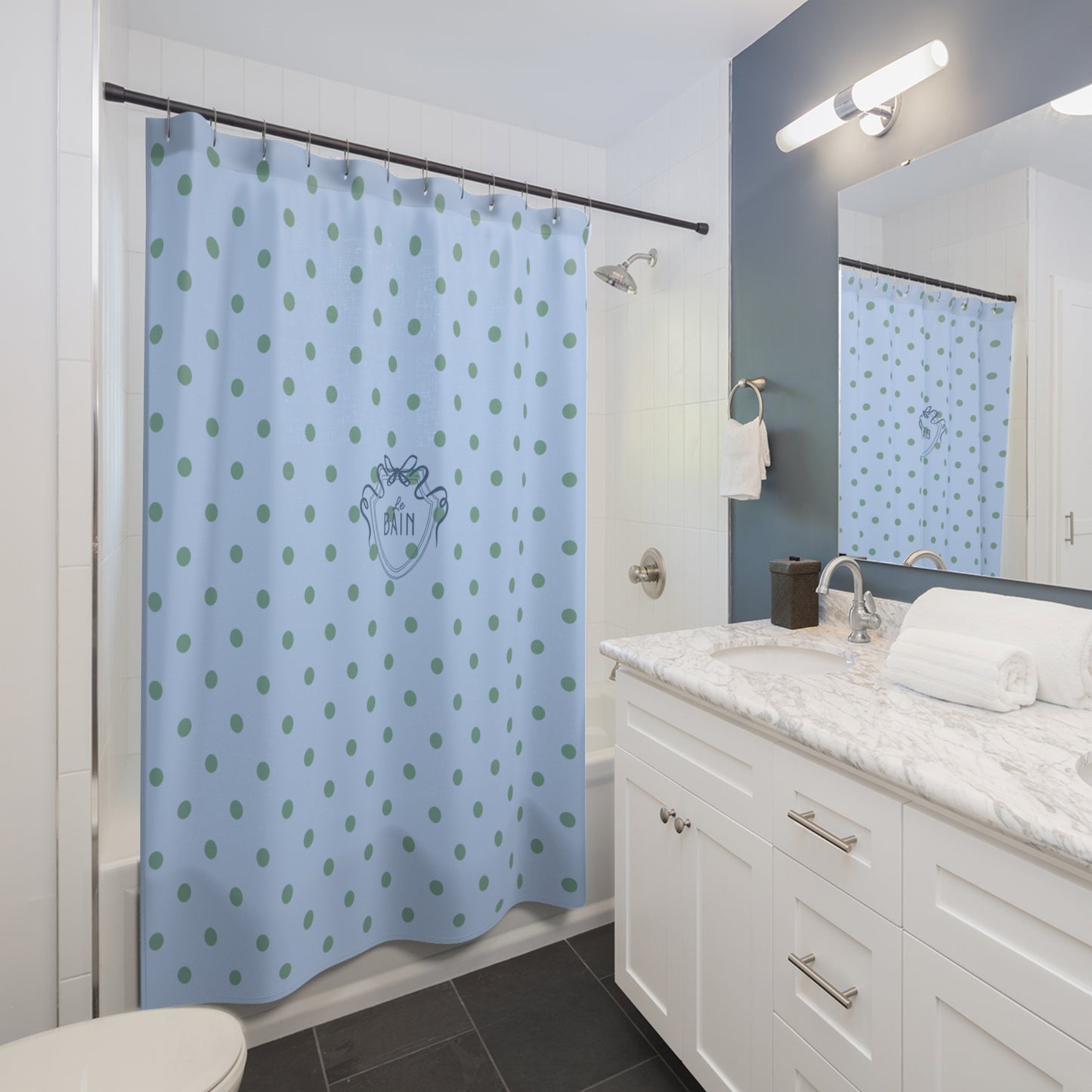 Bathroom with a blue shower curtain with green polka dots, white vanity, and mirror.