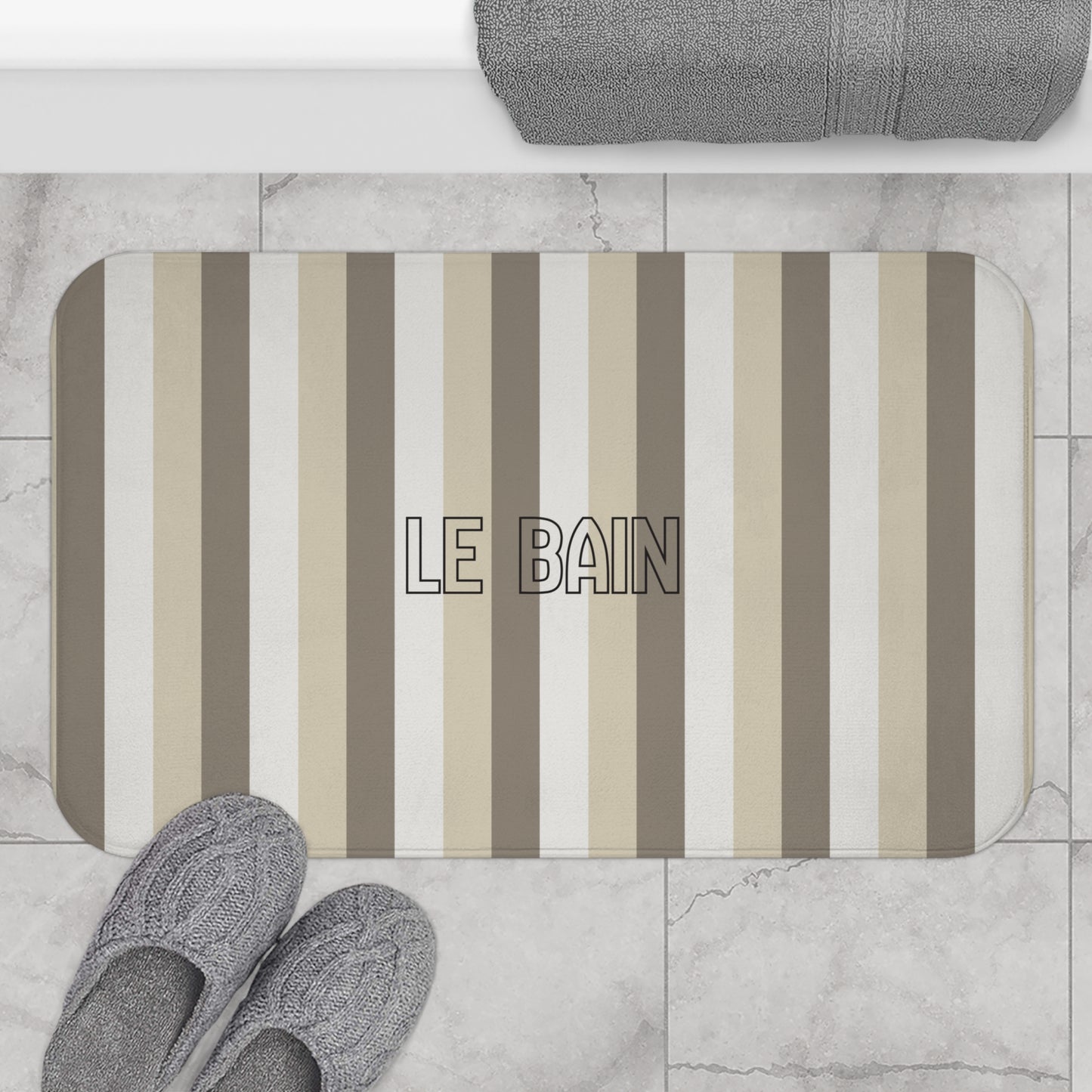 Striped bath mat with 'LE BAIN' text on a bathroom floor.