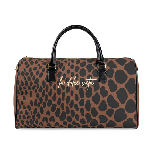 A brown and black leopard-print duffle bag with black handles and gold hardware, featuring the text 'la dolce vita' in gold script on the front, set against a plain white background.