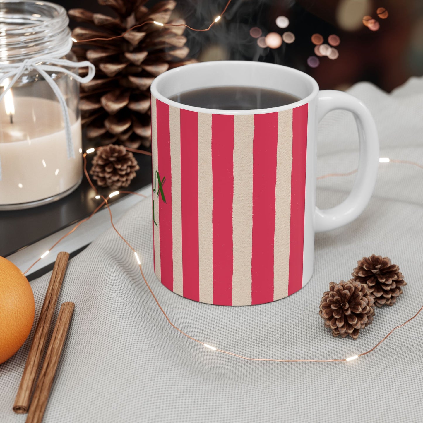 Striped mug with a festive design on a table with candles and pinecones.