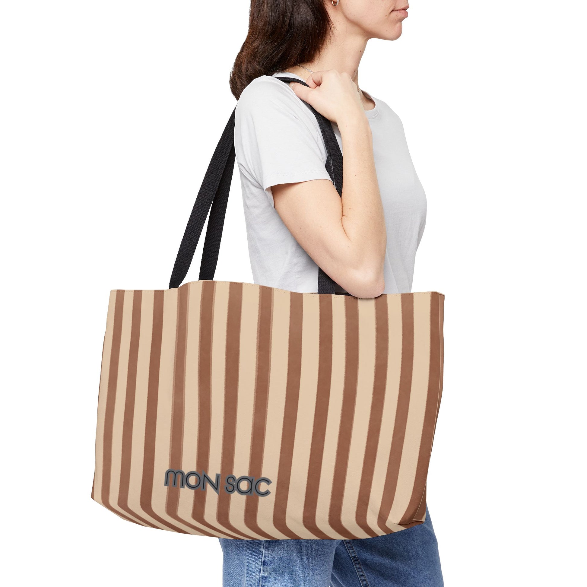 Person holding a striped tote bag with 'MON SAC' branding on a white background