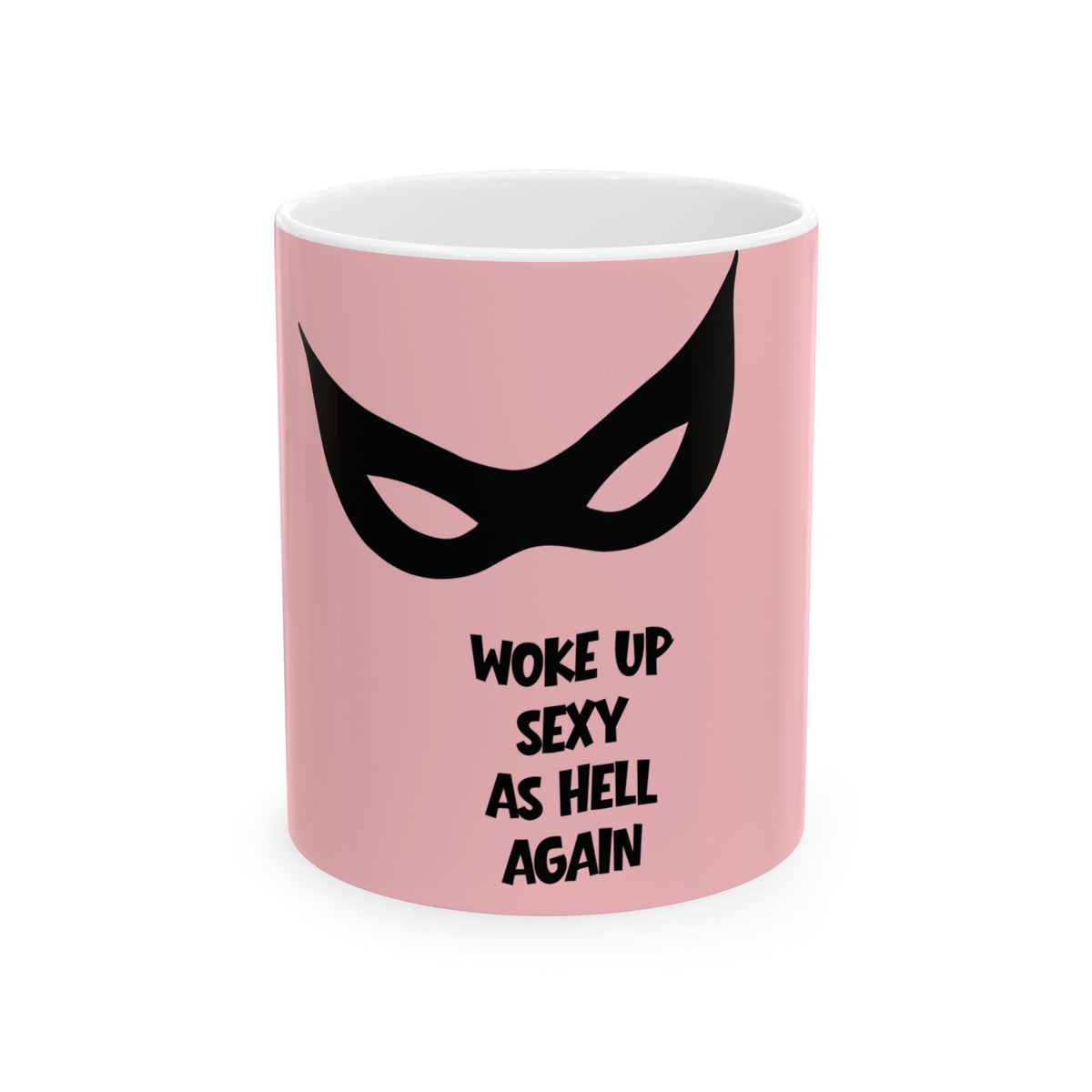 A pink ceramic mug with a black graphic of a stylized mask and the text 'WOKE UP SEXY AS HELL AGAIN' printed on the front, shown against a plain white background.