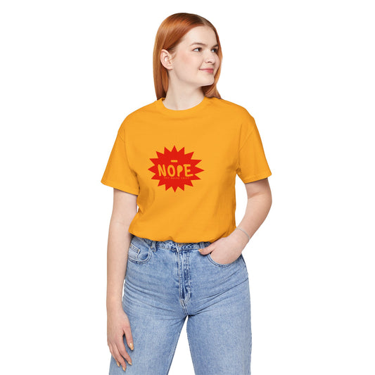 A woman with red hair wearing a cropped yellow t-shirt with a red starburst graphic that says 'NOPE' in yellow, paired with light blue jeans, against a plain white background.