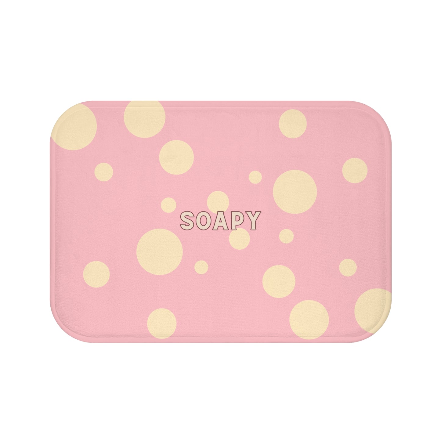 A rectangular pink bath mat with rounded corners, decorated with scattered light yellow polka dots and the word 'SOAPY' printed in the center, shown on a plain white background.