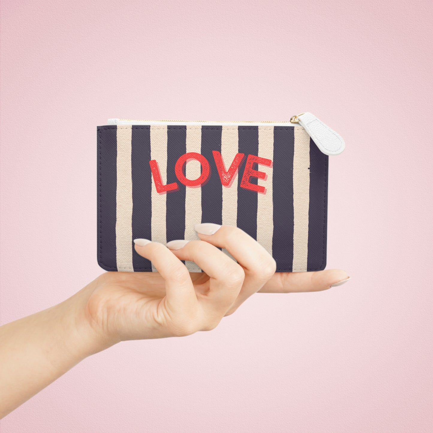 Striped pouch with 'LOVE' text held by a hand against a pink background