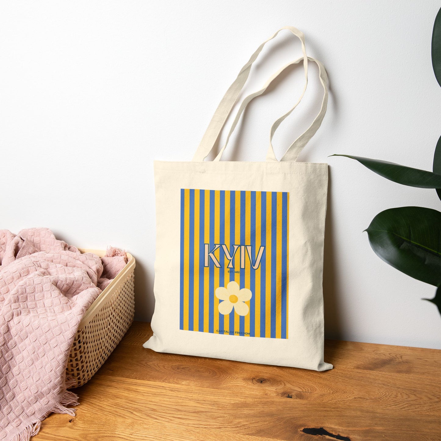 Tote bag with 'KYIV' and a flower design on a wooden surface with a white wall background.