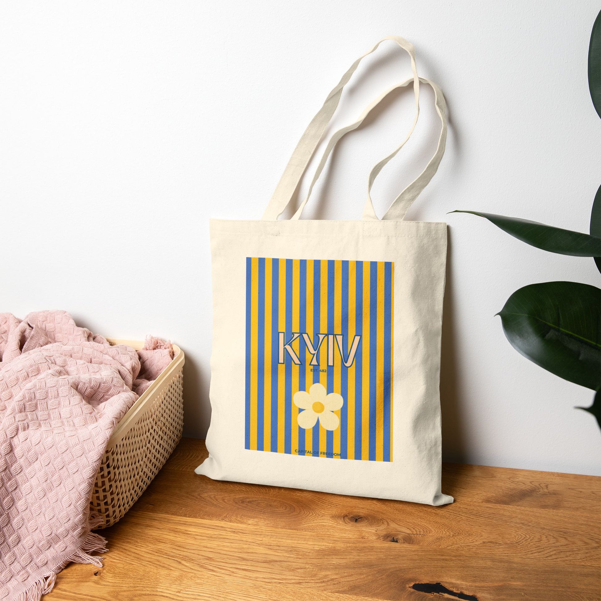Tote bag with 'KYIV' and a flower design on a wooden surface with a white wall background.
