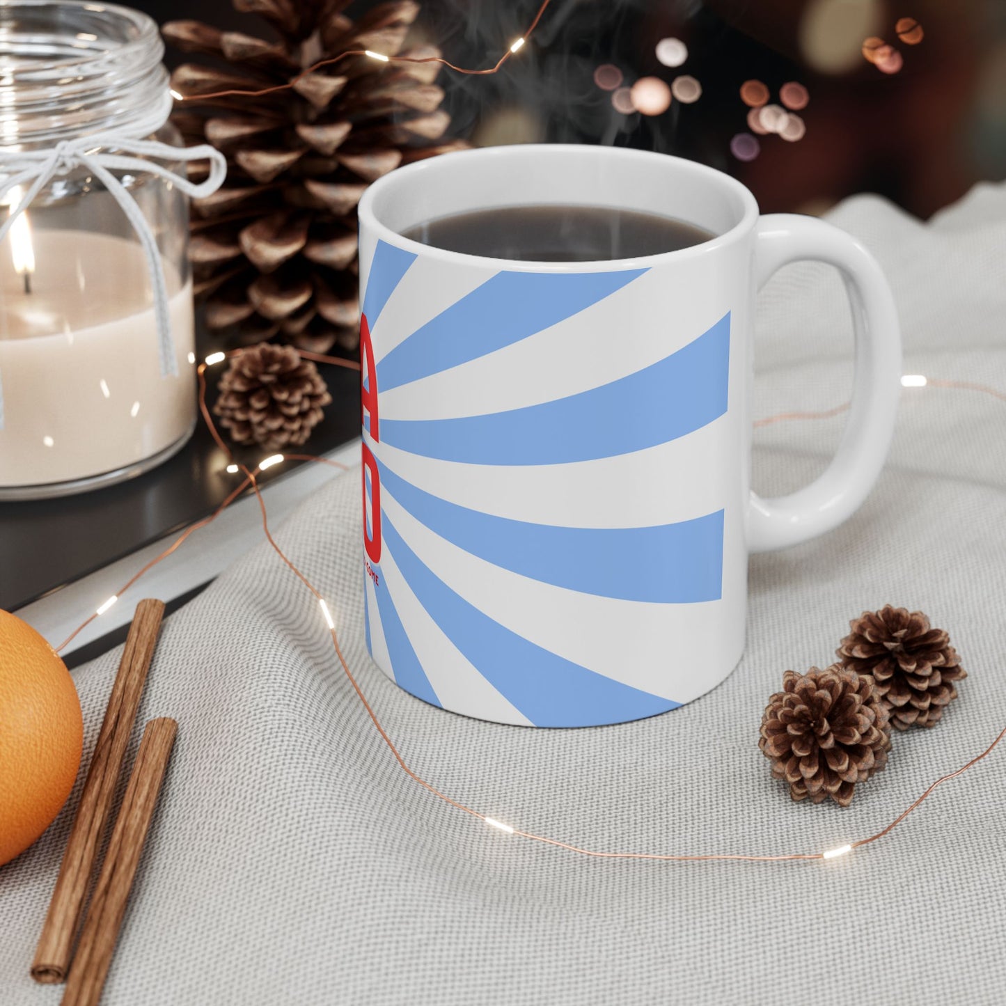 White mug with blue and red design on a table with decorative items