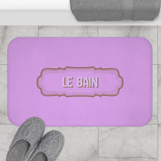 Purple bath mat with 'LE BAIN' text on a marble floor with gray slippers and towel.