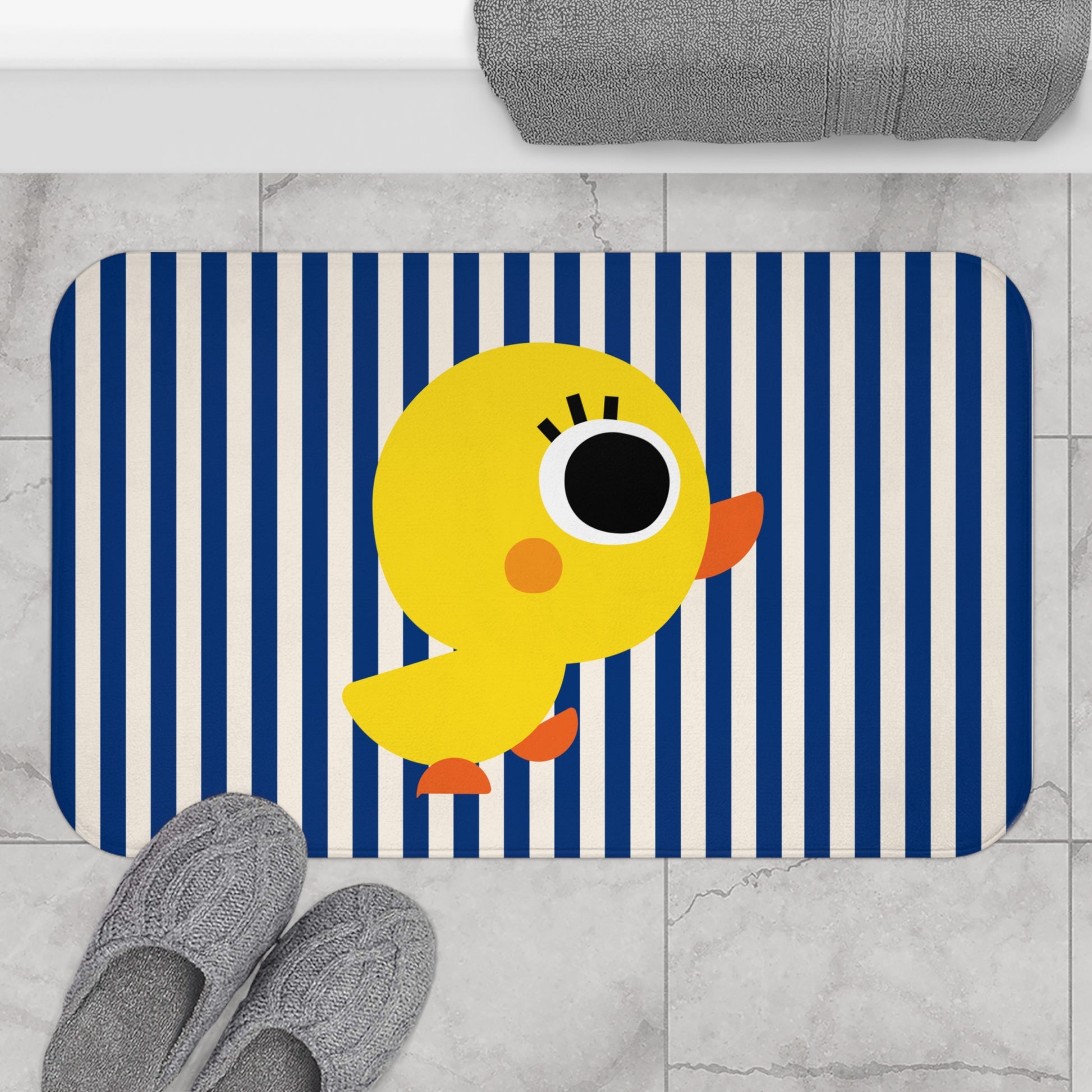 Bath mat with a yellow duck design on a blue and white striped background