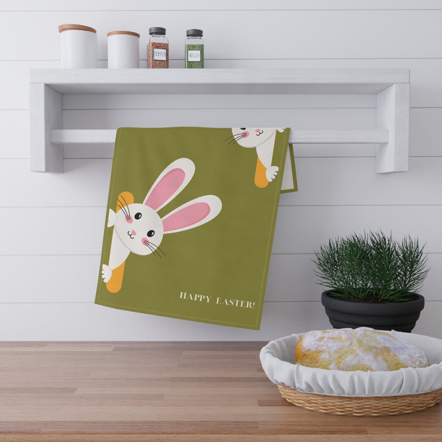 Green towel with Easter bunny design hanging on a wooden shelf.