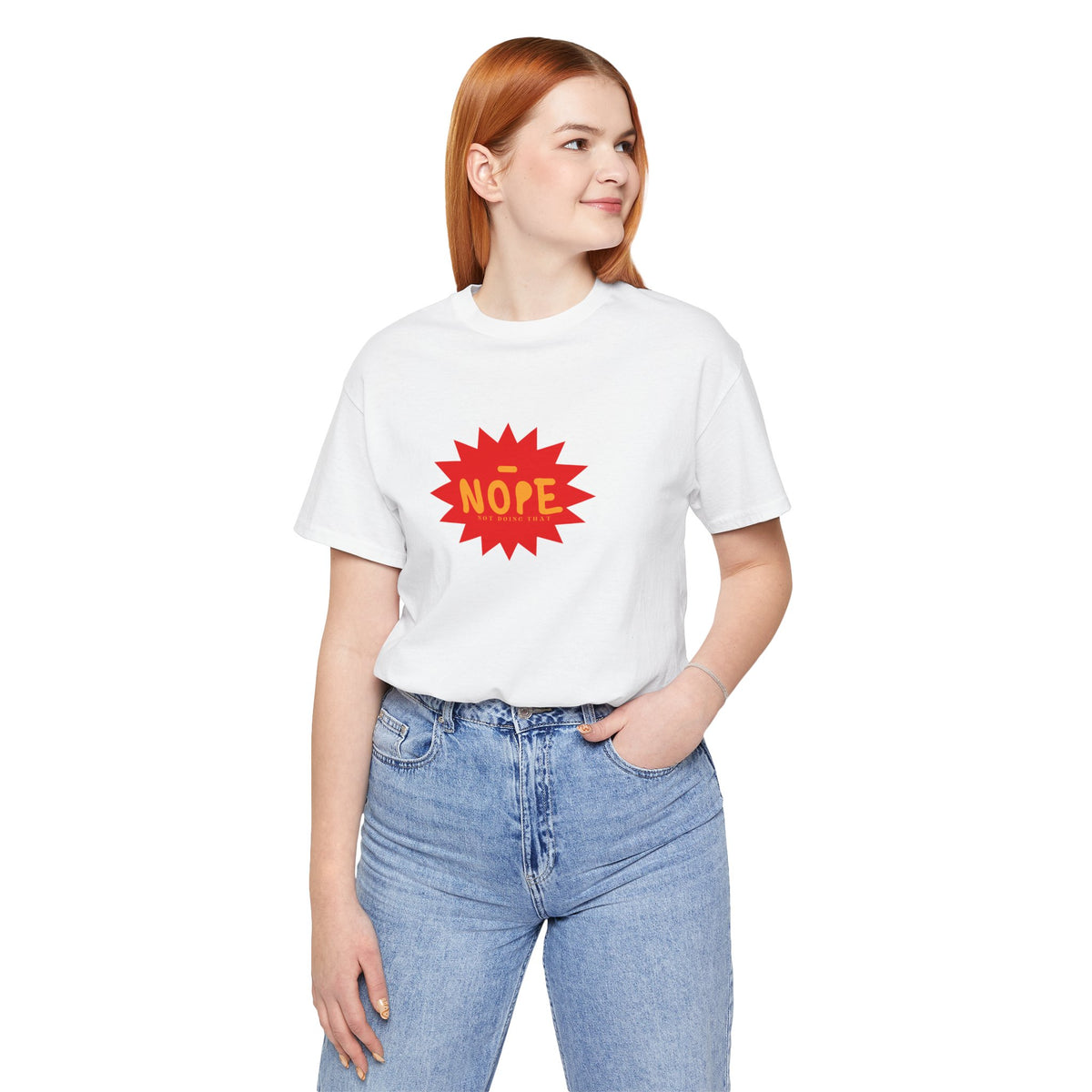 A woman with red hair wearing a white short-sleeve t-shirt with a red starburst graphic that says 'NOPE' in yellow, paired with light blue jeans, against a plain white background.