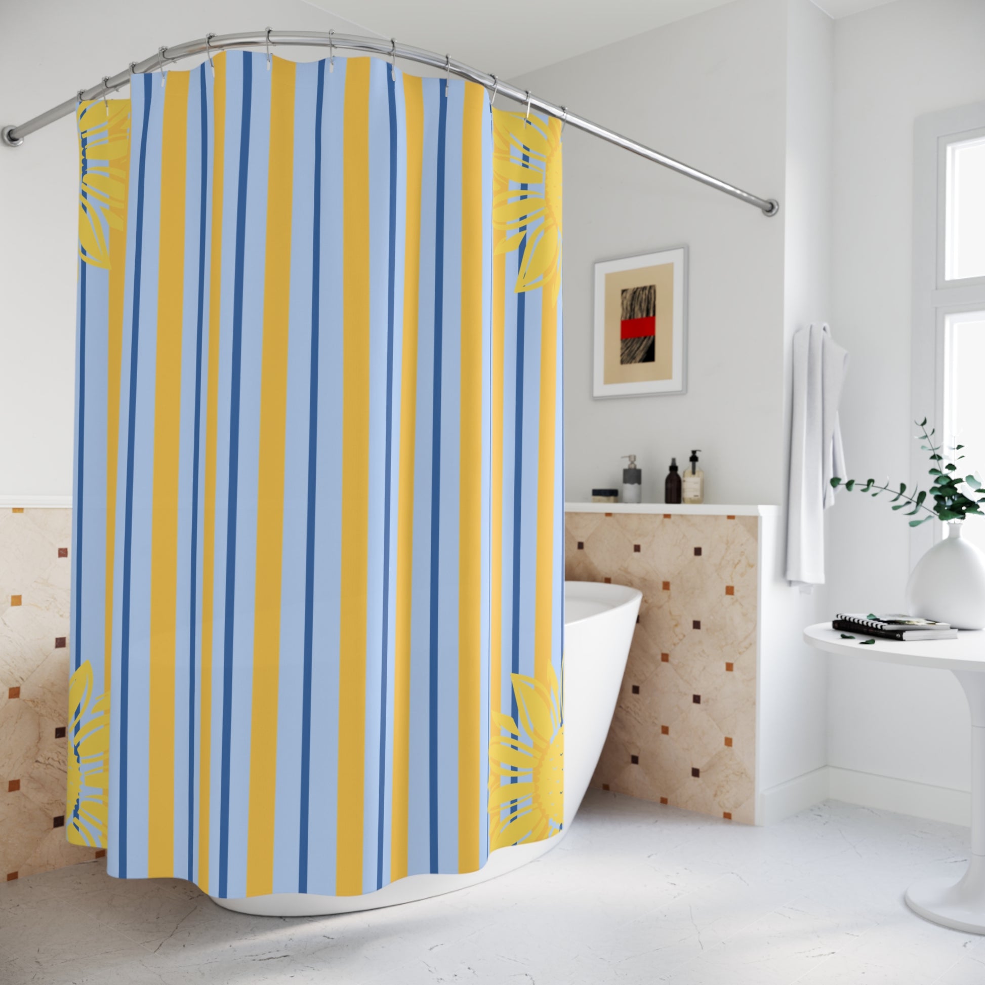 A shower curtain with vertical stripes in blue, yellow, and white, featuring yellow tropical leaf patterns at the corners, hanging in a bright white bathroom.