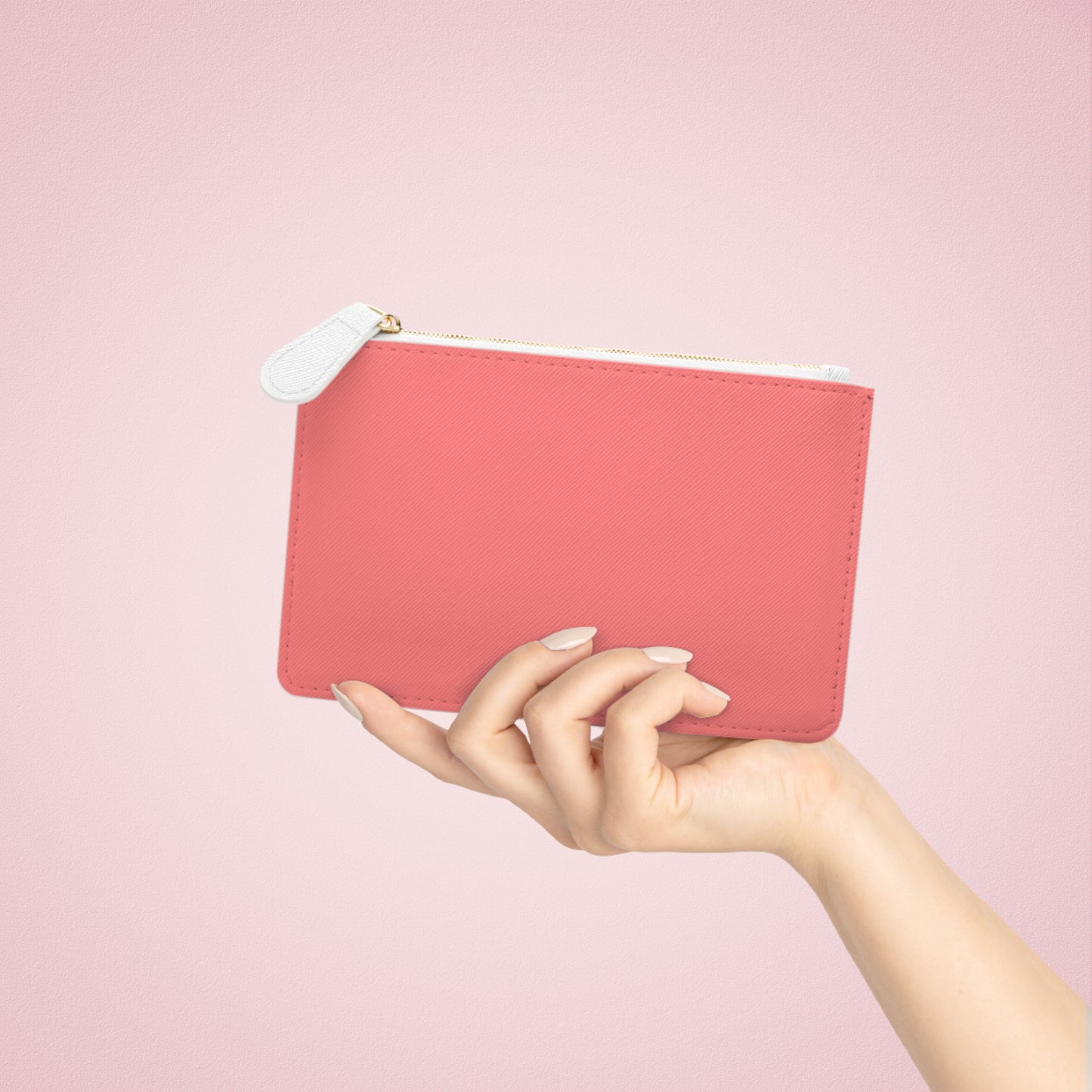 Hand holding a pink pouch against a pink background