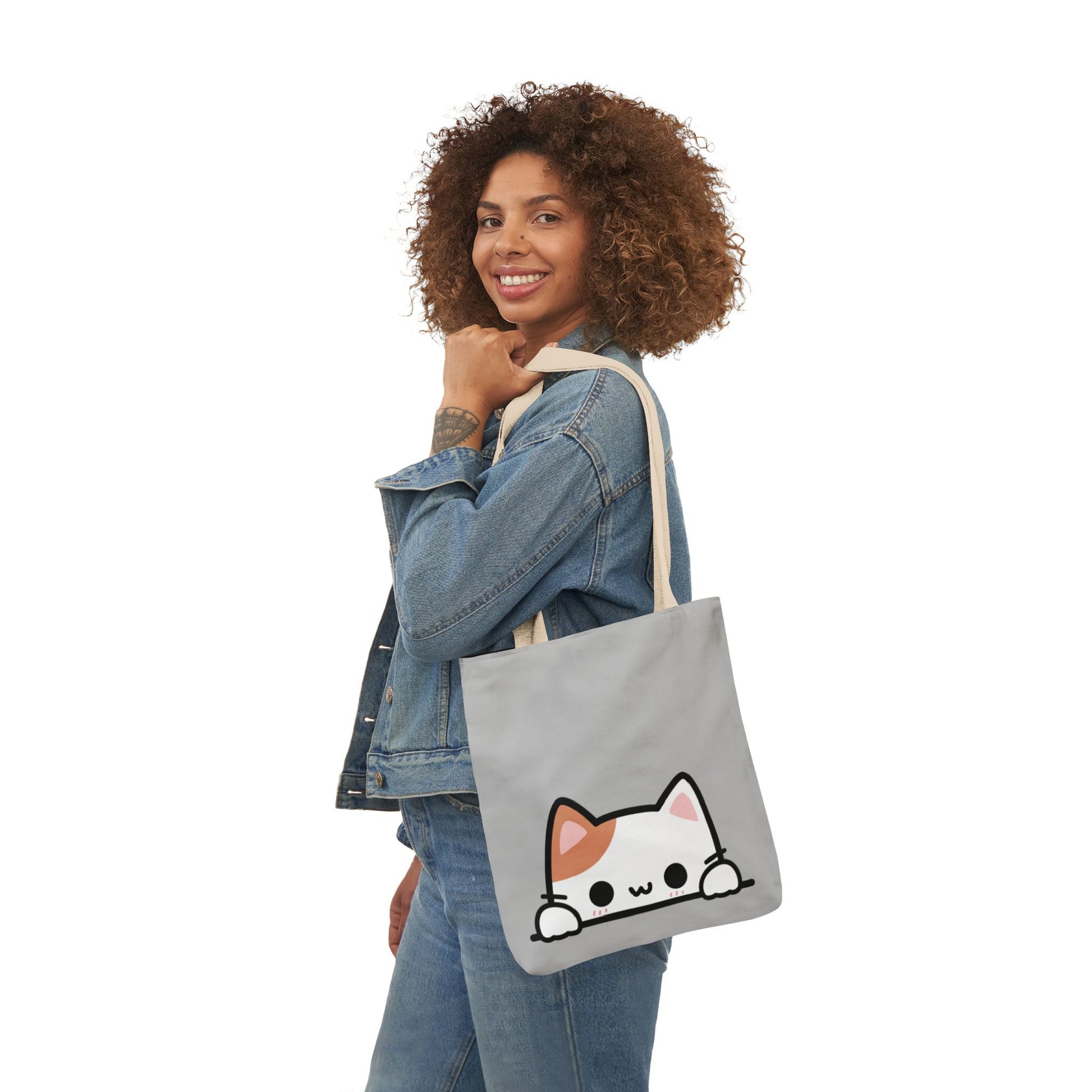 Woman holding a gray tote bag with a cat design on a white background