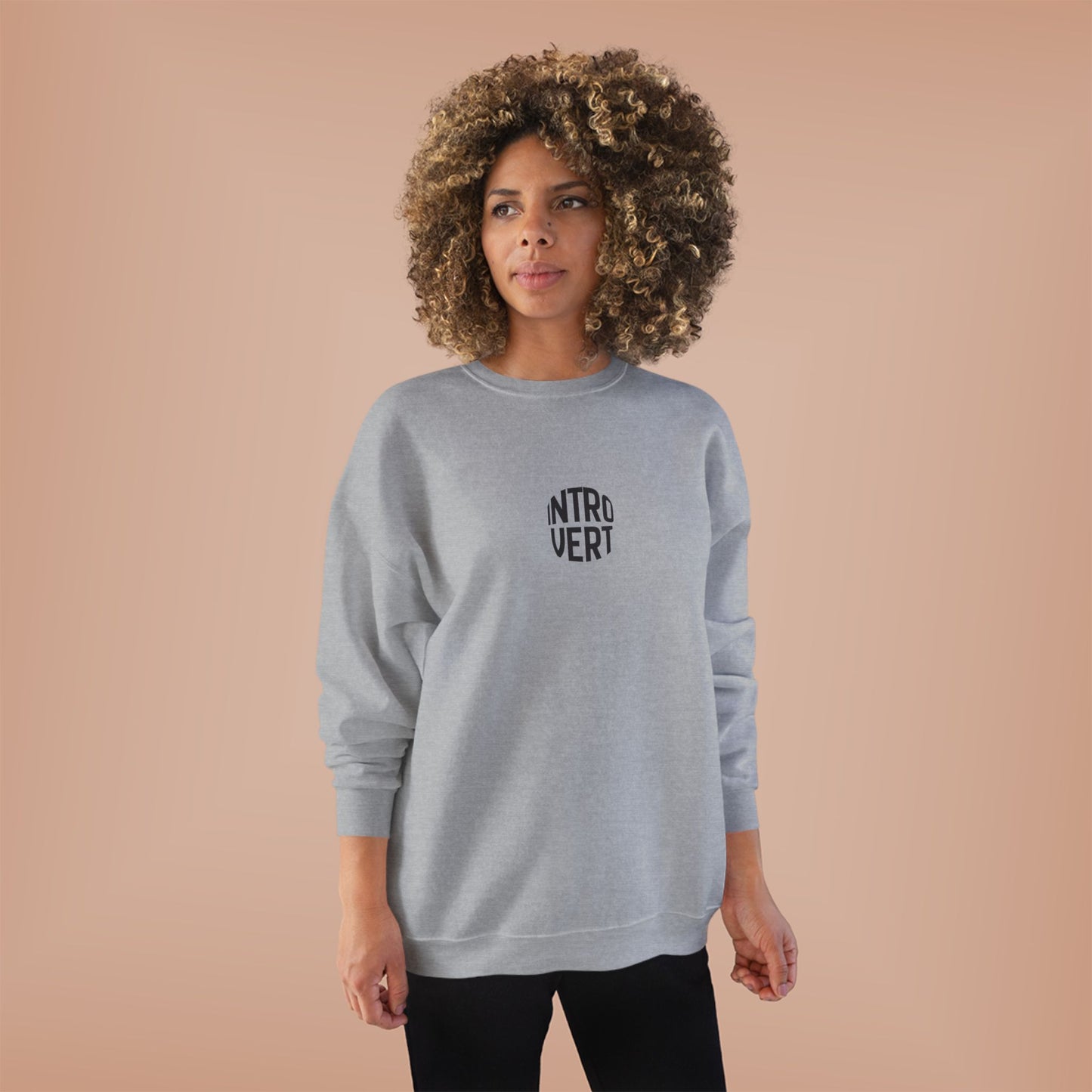 Woman wearing a gray sweatshirt with 'INTROVERT' text on a beige background