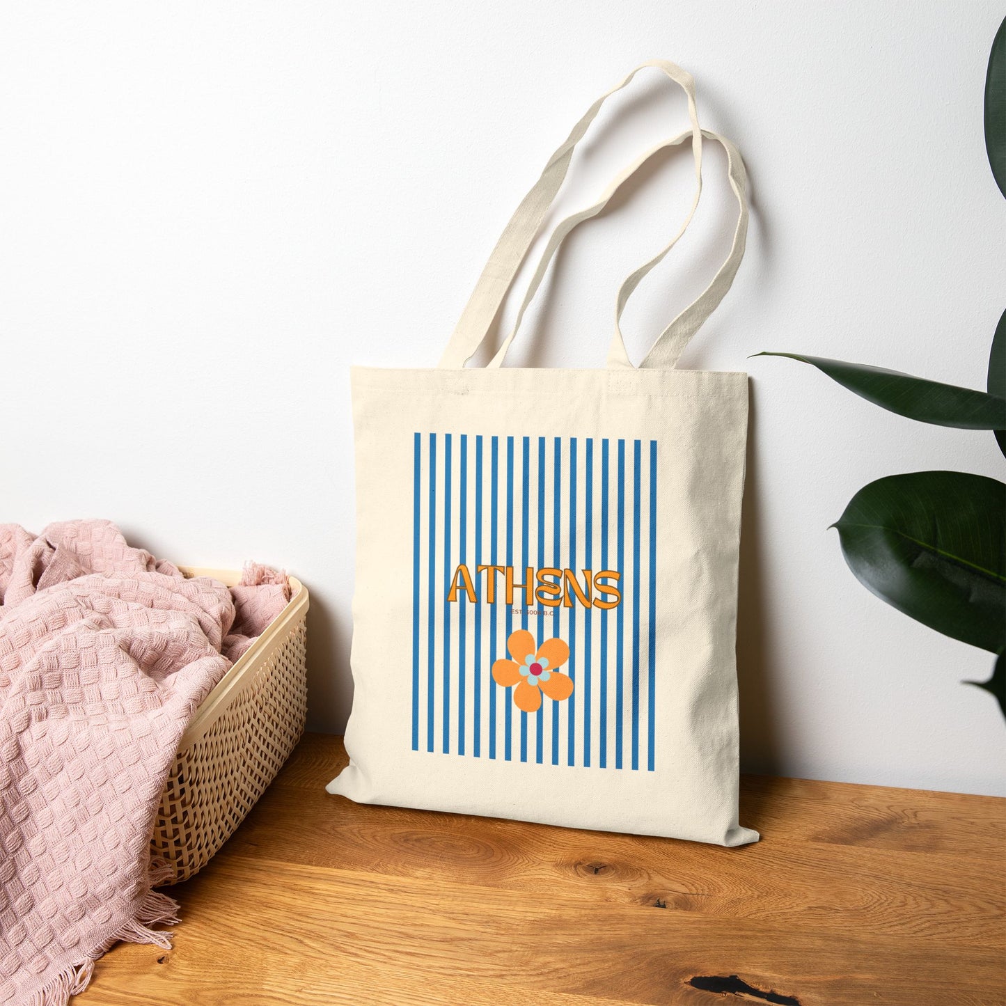 Tote bag with 'Athens' design on a wooden surface with a plant in the background
